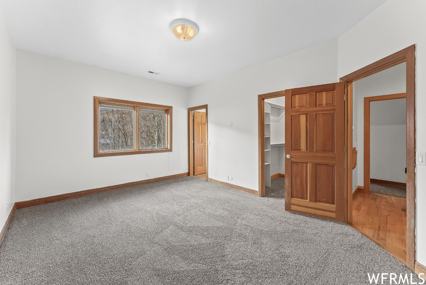 Unfurnished bedroom with a spacious closet, a closet, and light hardwood / wood-style floors