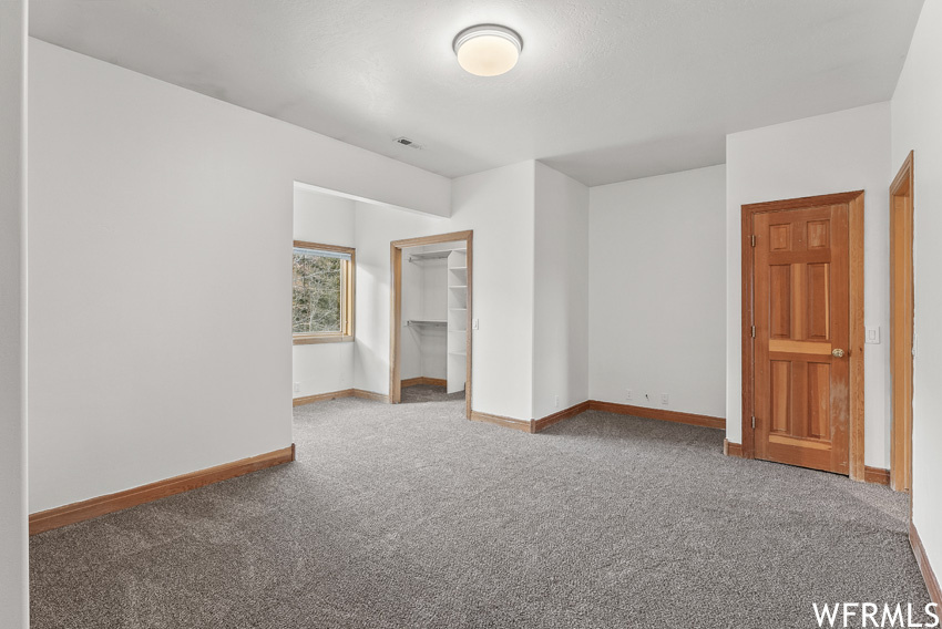Unfurnished bedroom with a spacious closet, light carpet, and a closet