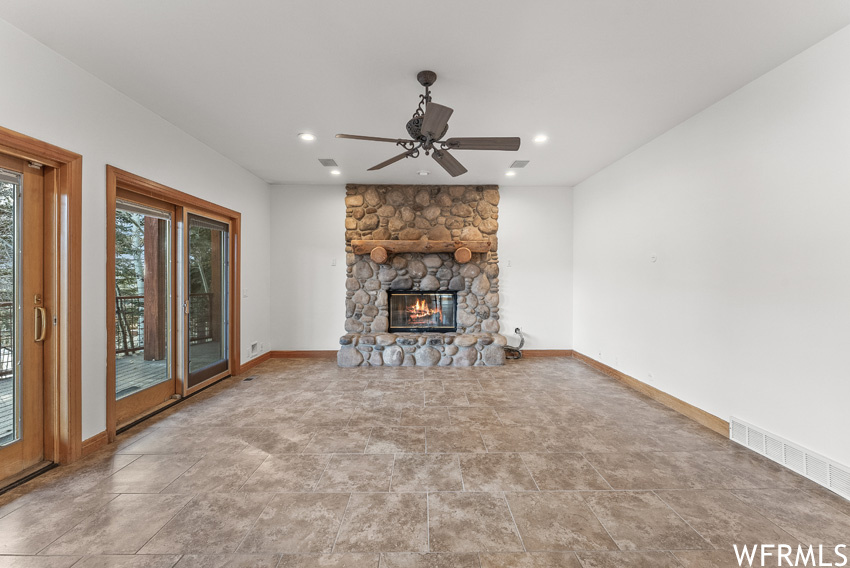 Unfurnished living room with ceiling fan, a fireplace, and light tile floors