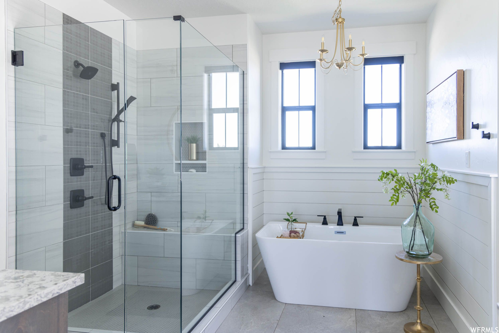 Bathroom featuring separate shower and tub, tile walls, tile floors, and an inviting chandelier
