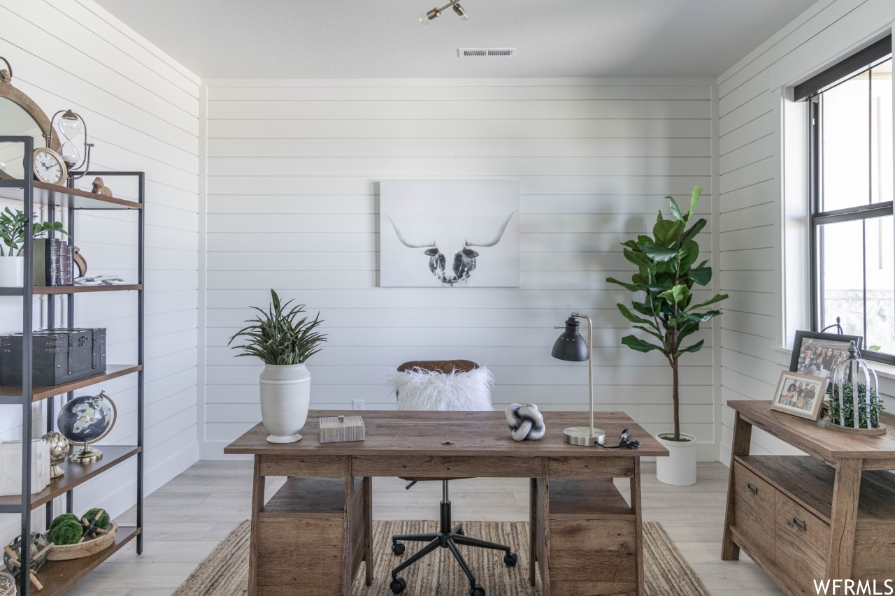 Home office featuring light hardwood / wood-style flooring and wood walls