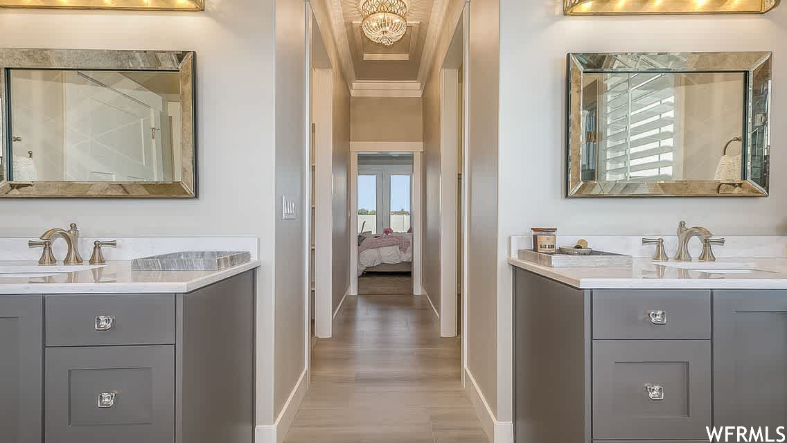 Bathroom with double vanity, ornamental molding, hardwood / wood-style floors, and a chandelier