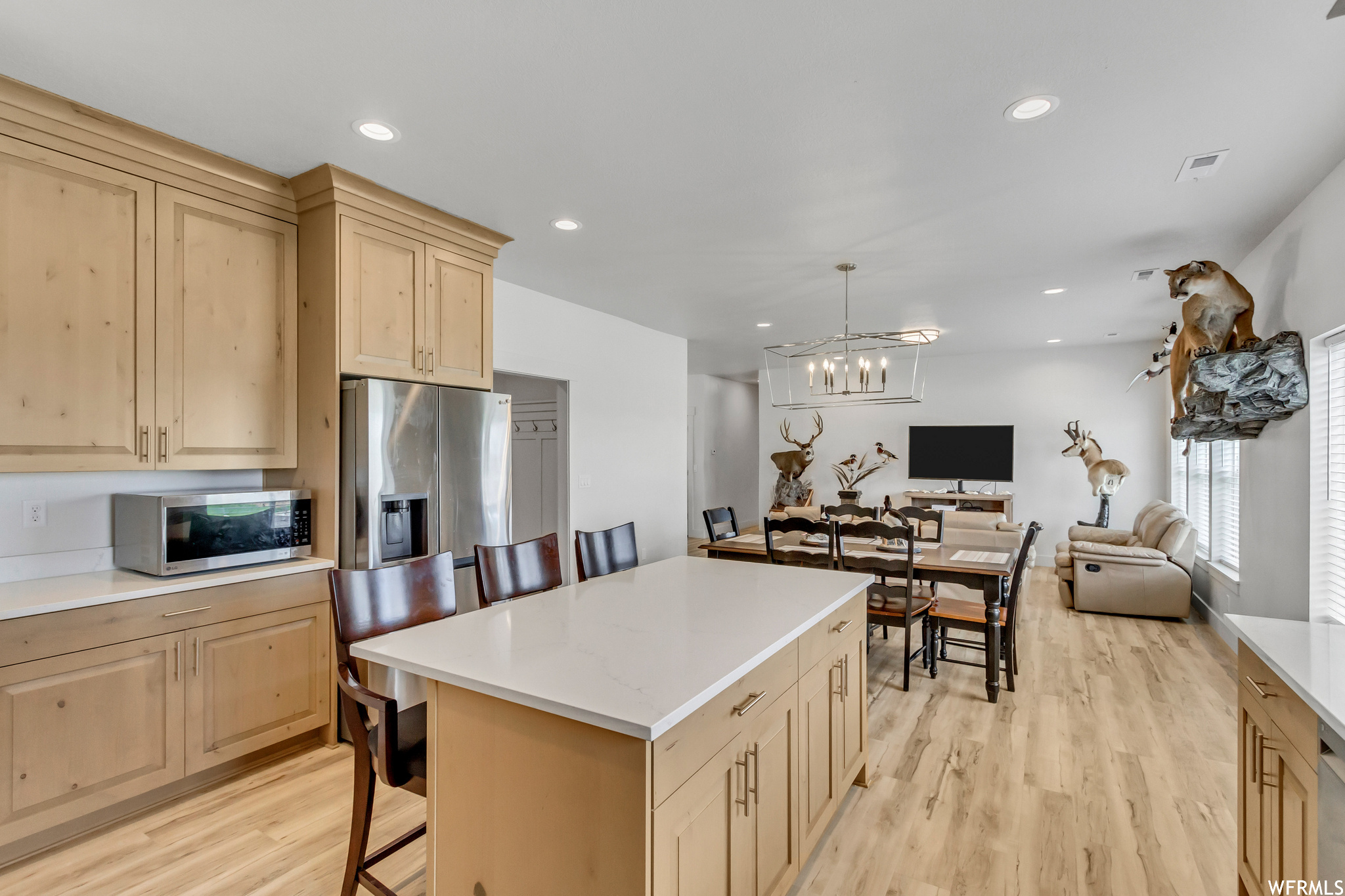 Kitchen featuring a breakfast bar area, a chandelier, appliances with stainless steel finishes, light hardwood / wood-style floors, and a kitchen island