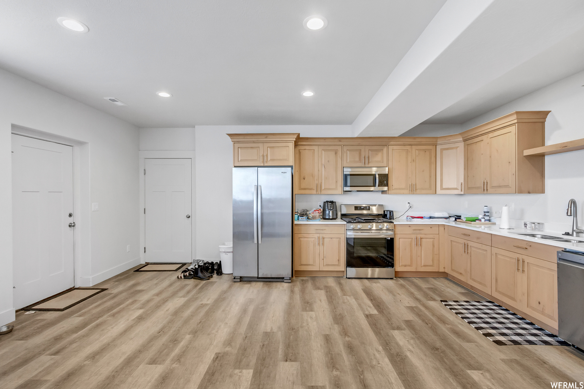 Kitchen with light brown cabinets, sink, appliances with stainless steel finishes, and light hardwood / wood-style floors