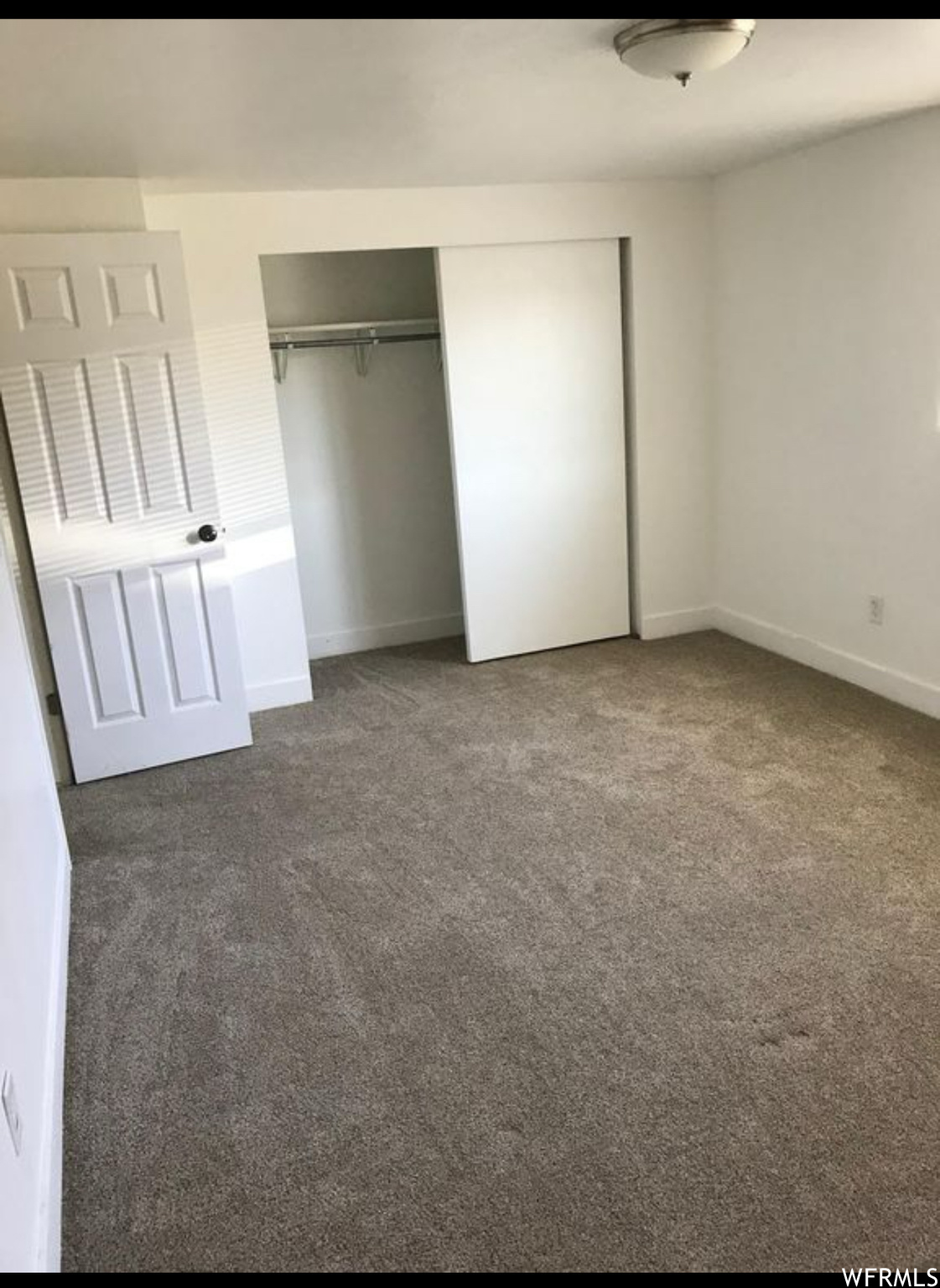 Master bedroom with dark colored carpet and a closet