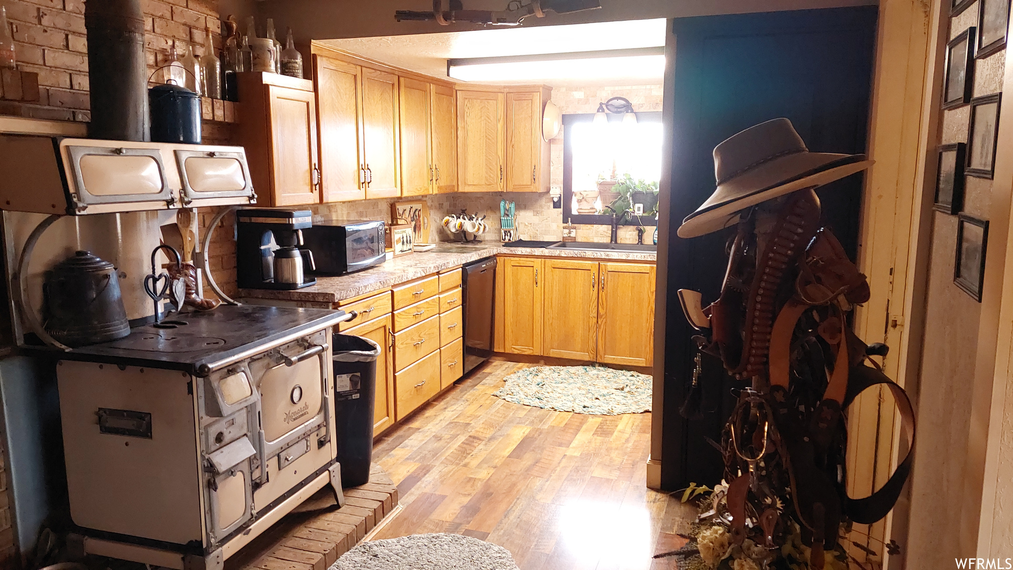 Kitchen with sink, light brown cabinetry, light wood-type flooring, dishwasher, and backsplash