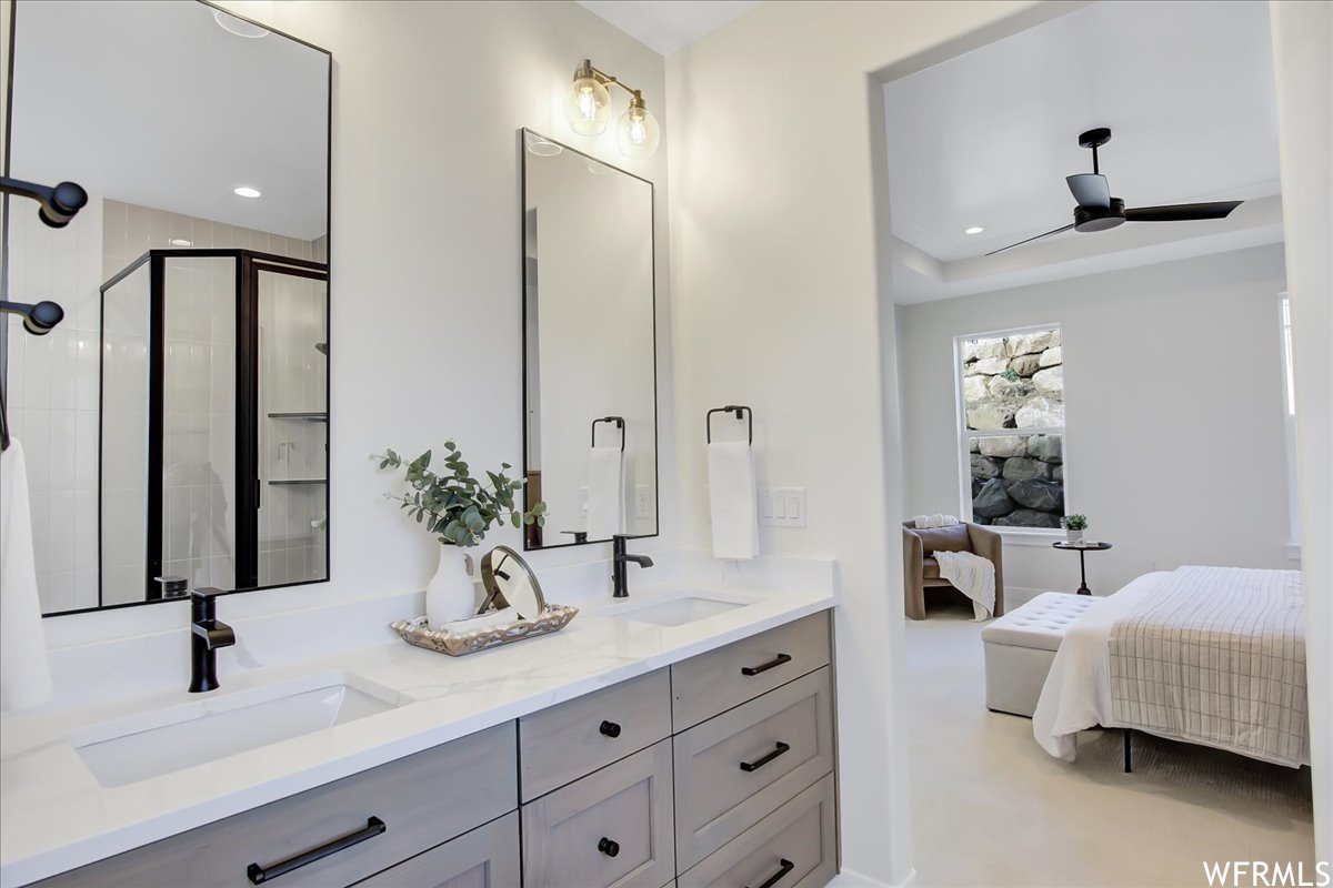Bathroom featuring dual vanity, ceiling fan, and a shower with shower door
