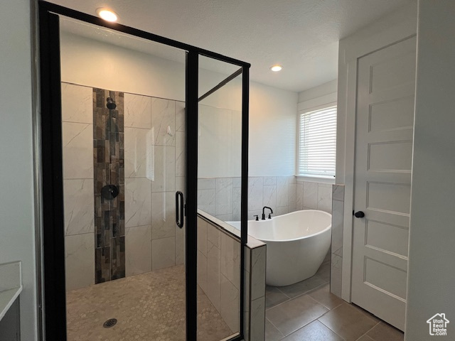 Bathroom featuring shower with separate bathtub, tile walls, and tile flooring