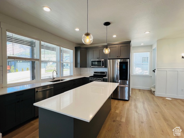 Kitchen featuring appliances with stainless steel finishes, backsplash, light hardwood / wood-style flooring, and a kitchen island