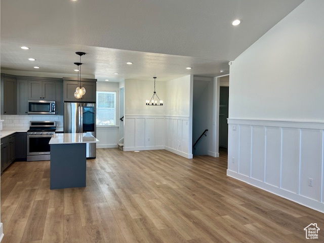Kitchen featuring a center island, tasteful backsplash, hanging light fixtures, stainless steel appliances, and wood-type flooring