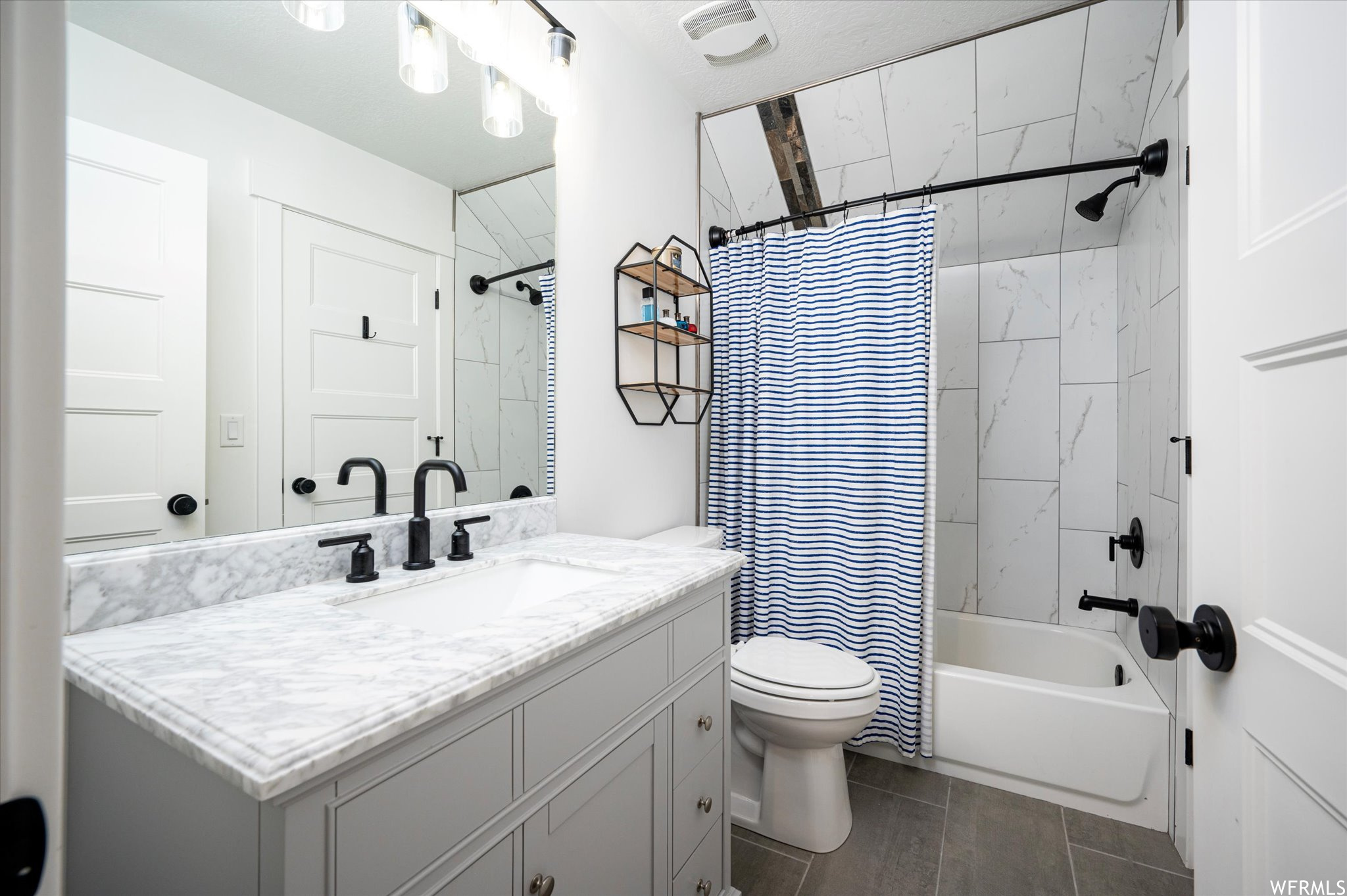 Full bathroom with toilet, vanity with extensive cabinet space, tile flooring, and shower / bath combo