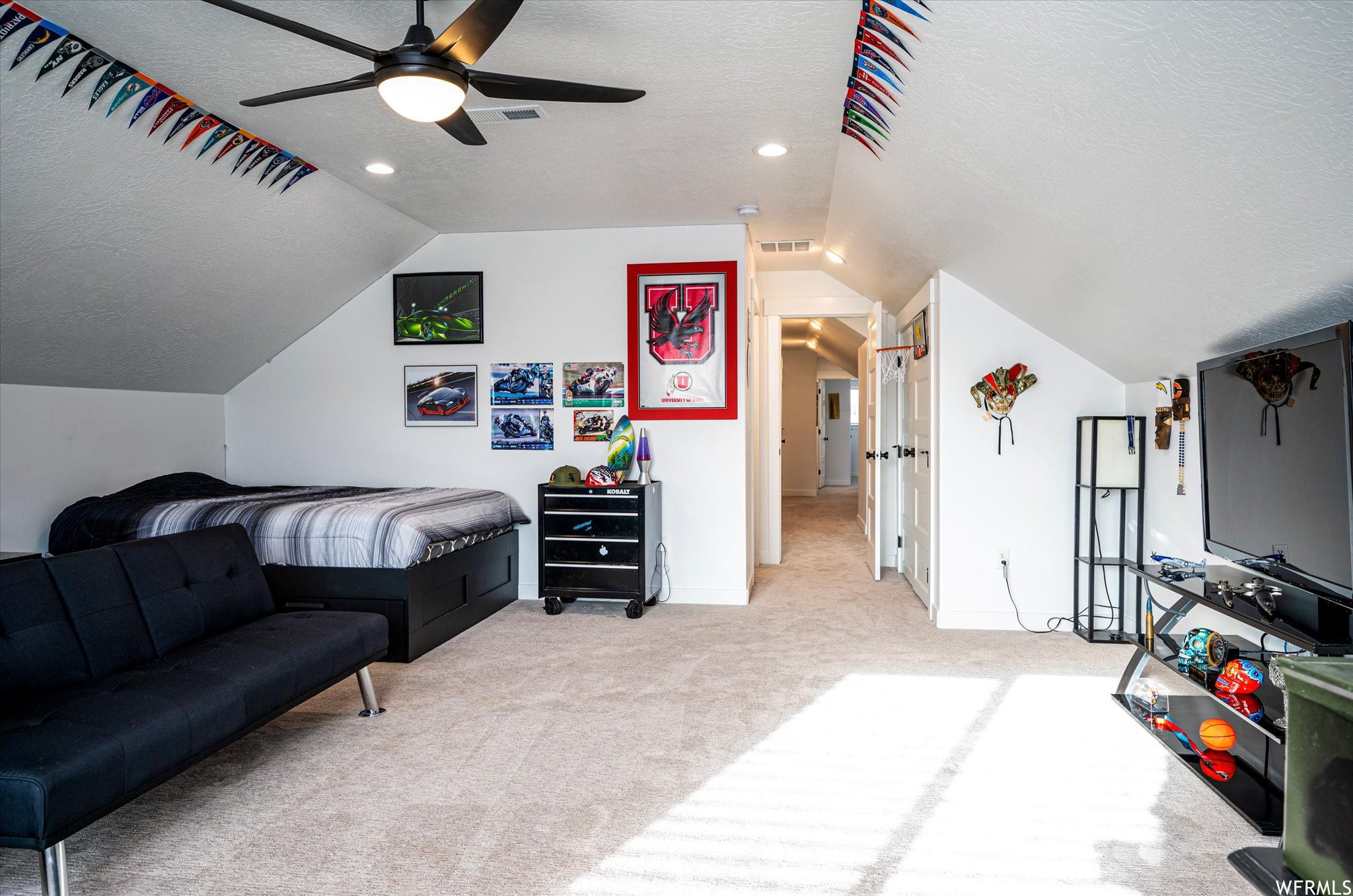 Bedroom with light colored carpet, ceiling fan, a textured ceiling, and vaulted ceiling