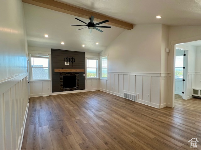 Unfurnished living room featuring lofted ceiling with beams, ceiling fan, a stone fireplace, and dark wood-type flooring