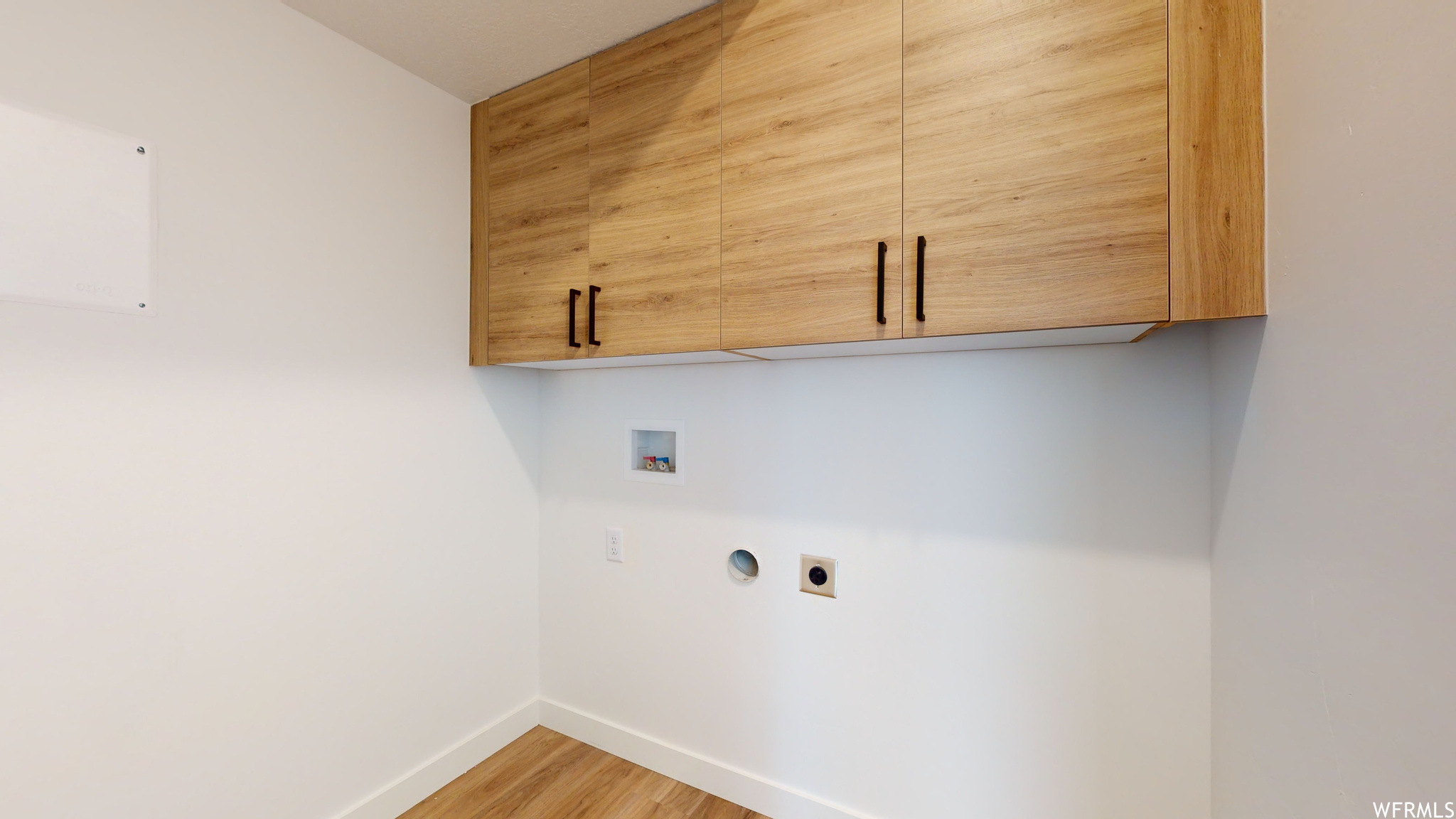 Laundry area featuring cabinets, light hardwood / wood-style floors, hookup for an electric dryer, and washer hookup