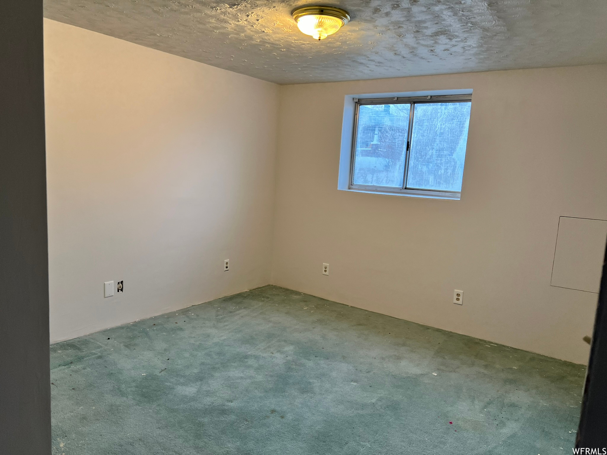 Carpeted spare room with a textured ceiling