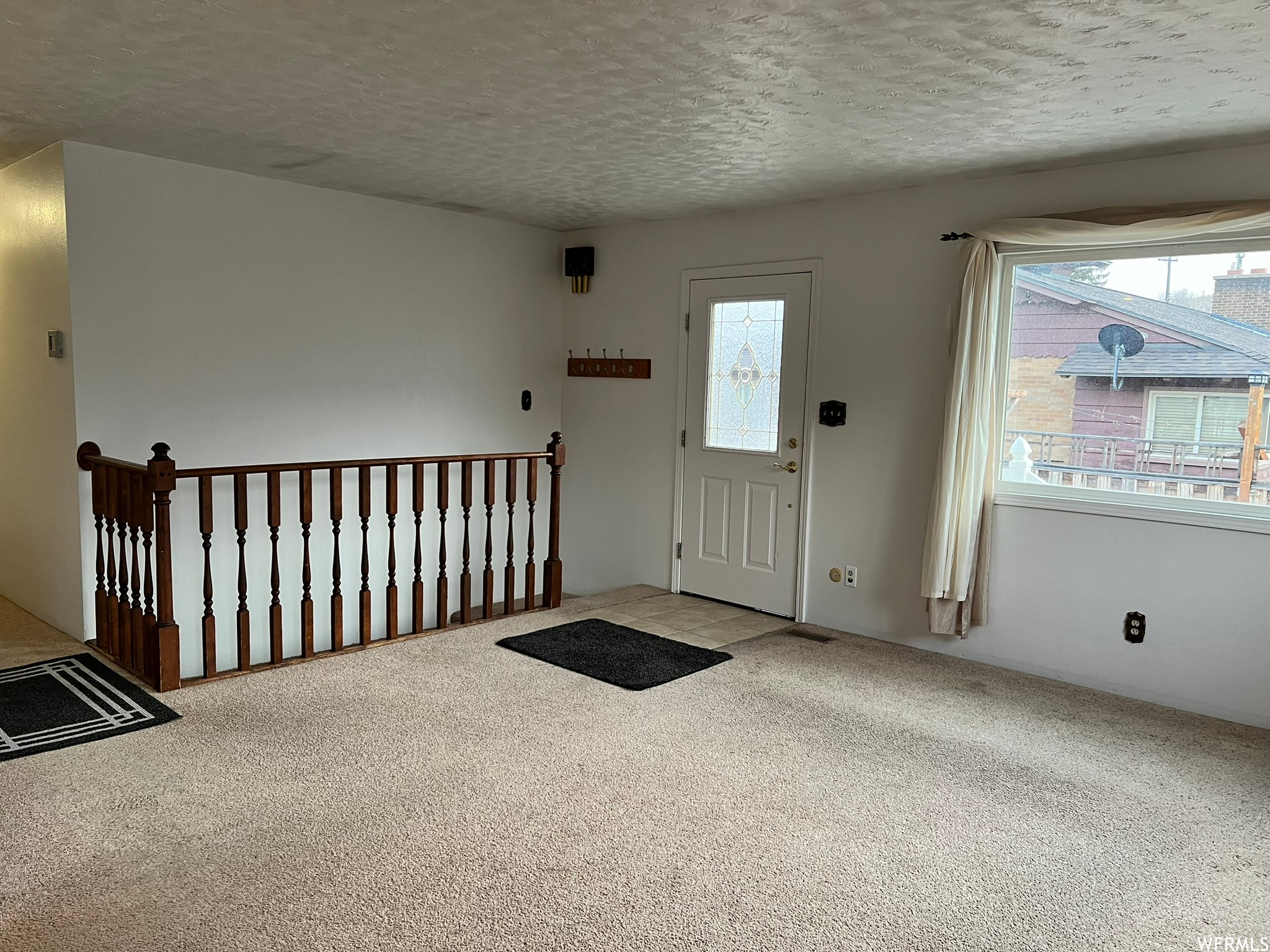 Carpeted entryway featuring a textured ceiling