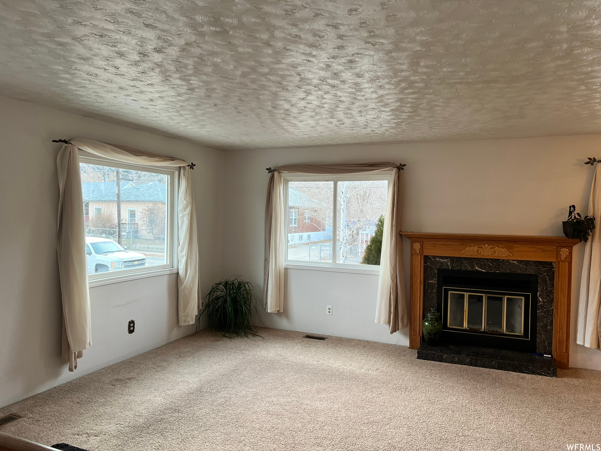 Unfurnished living room featuring a premium fireplace, a textured ceiling, and light colored carpet