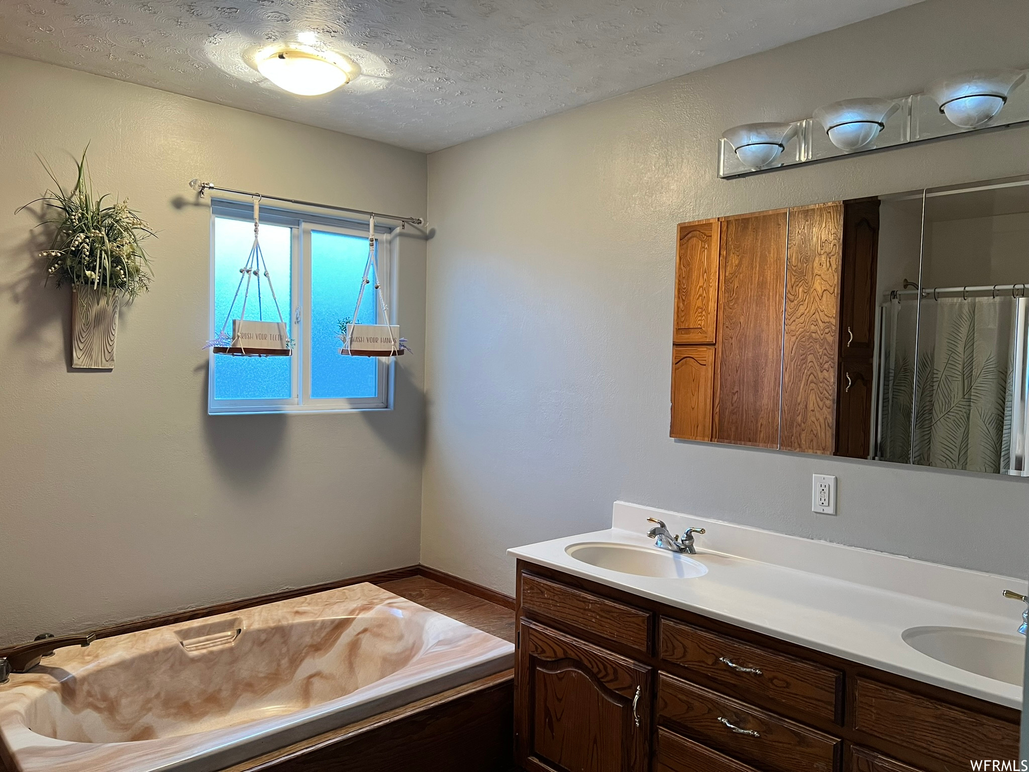 Bathroom featuring a textured ceiling and double sink vanity