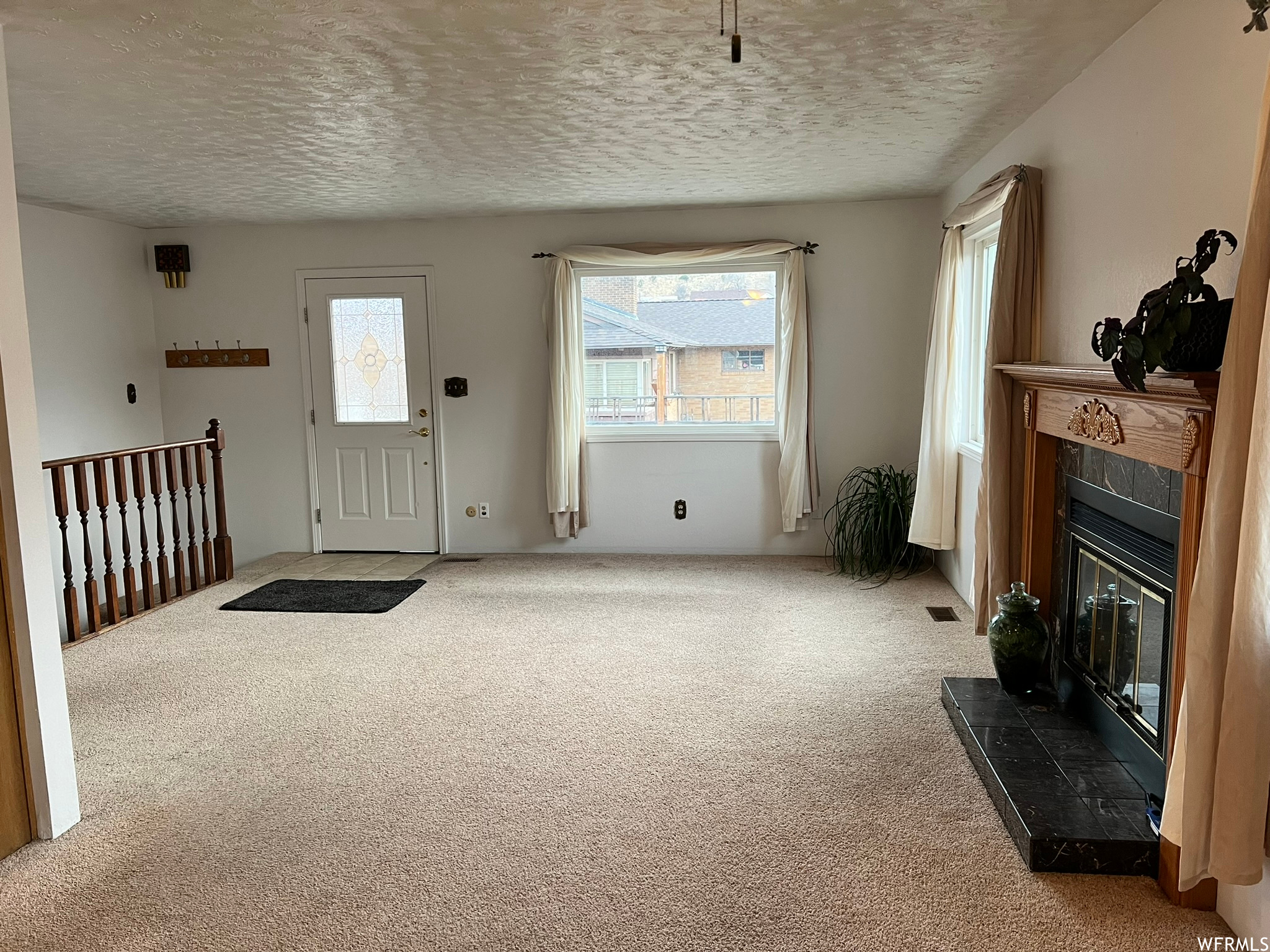 Living room with light colored carpet, a textured ceiling, and a tiled fireplace