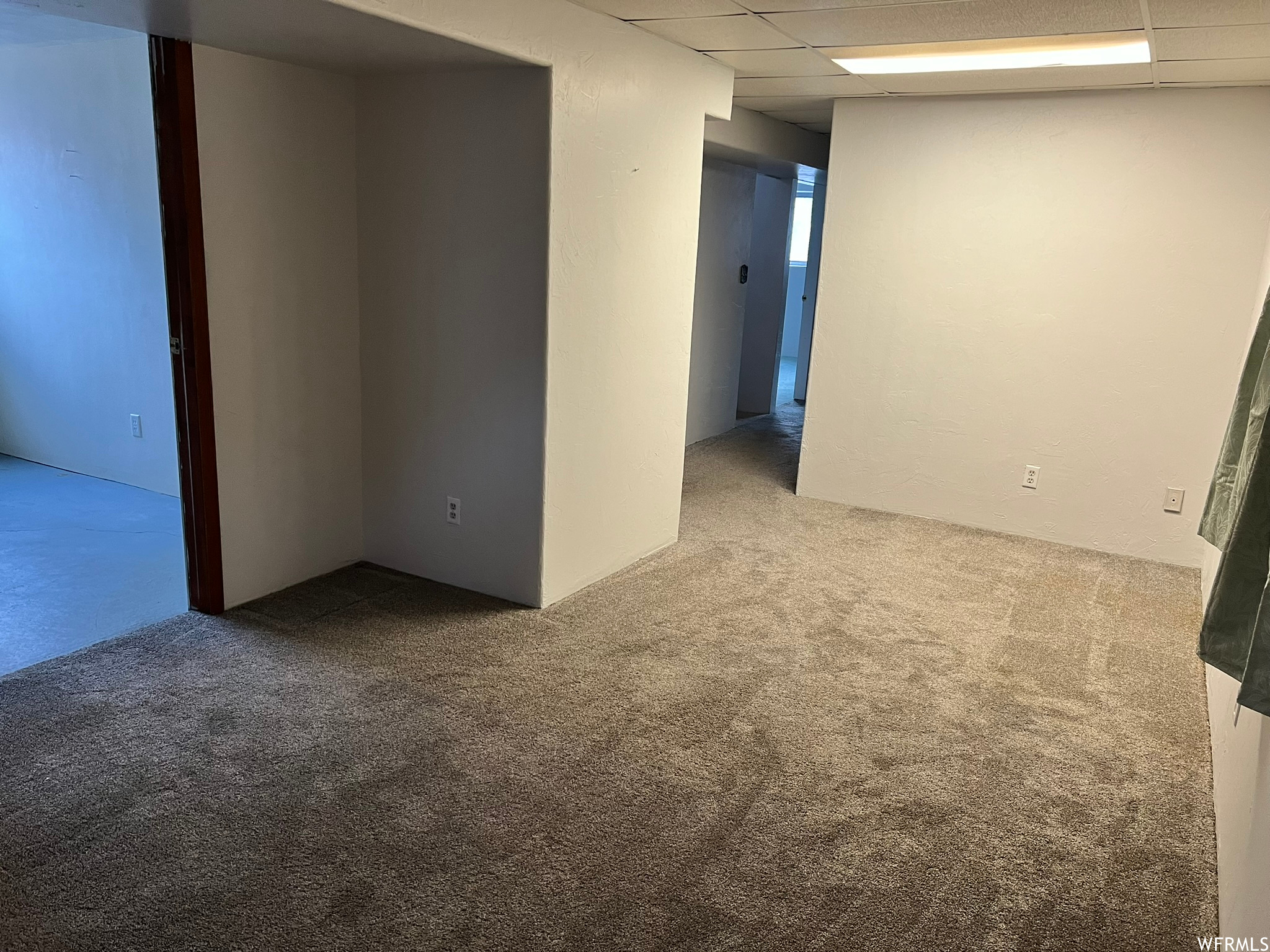 Basemen family room with a drop ceiling and light colored carpet