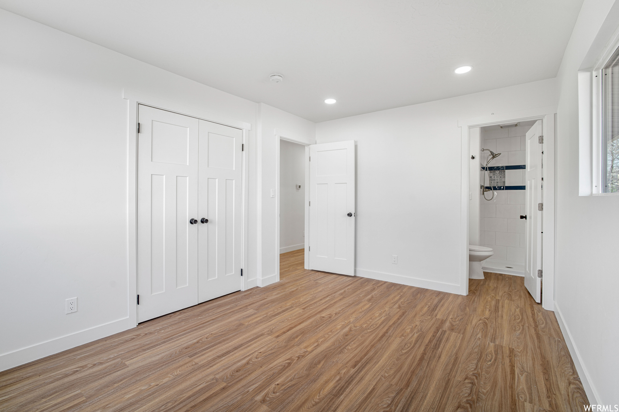 Unfurnished bedroom with ensuite bathroom, light hardwood / wood-style flooring, and a closet
