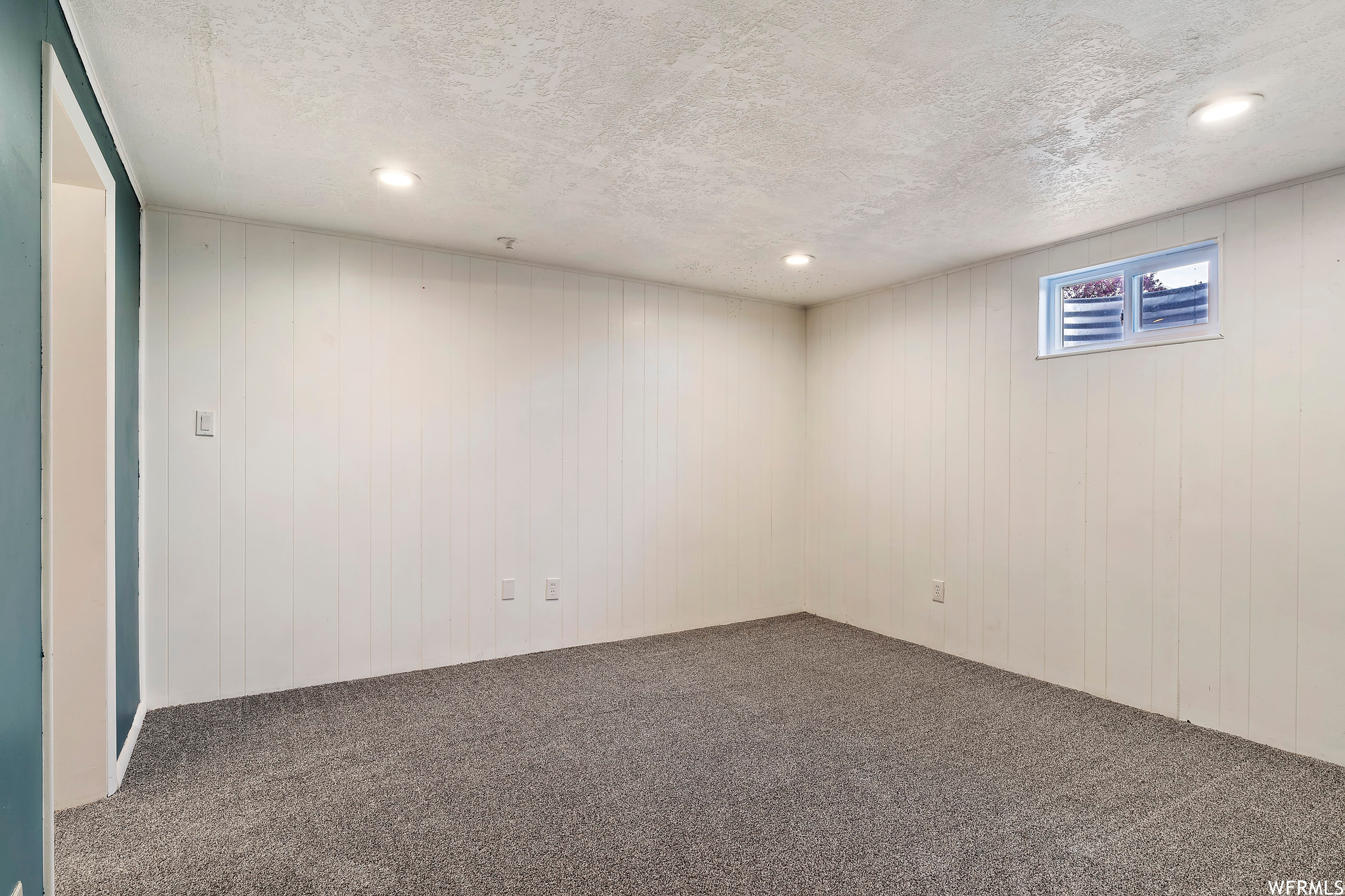 Basement with a textured ceiling and dark colored carpet