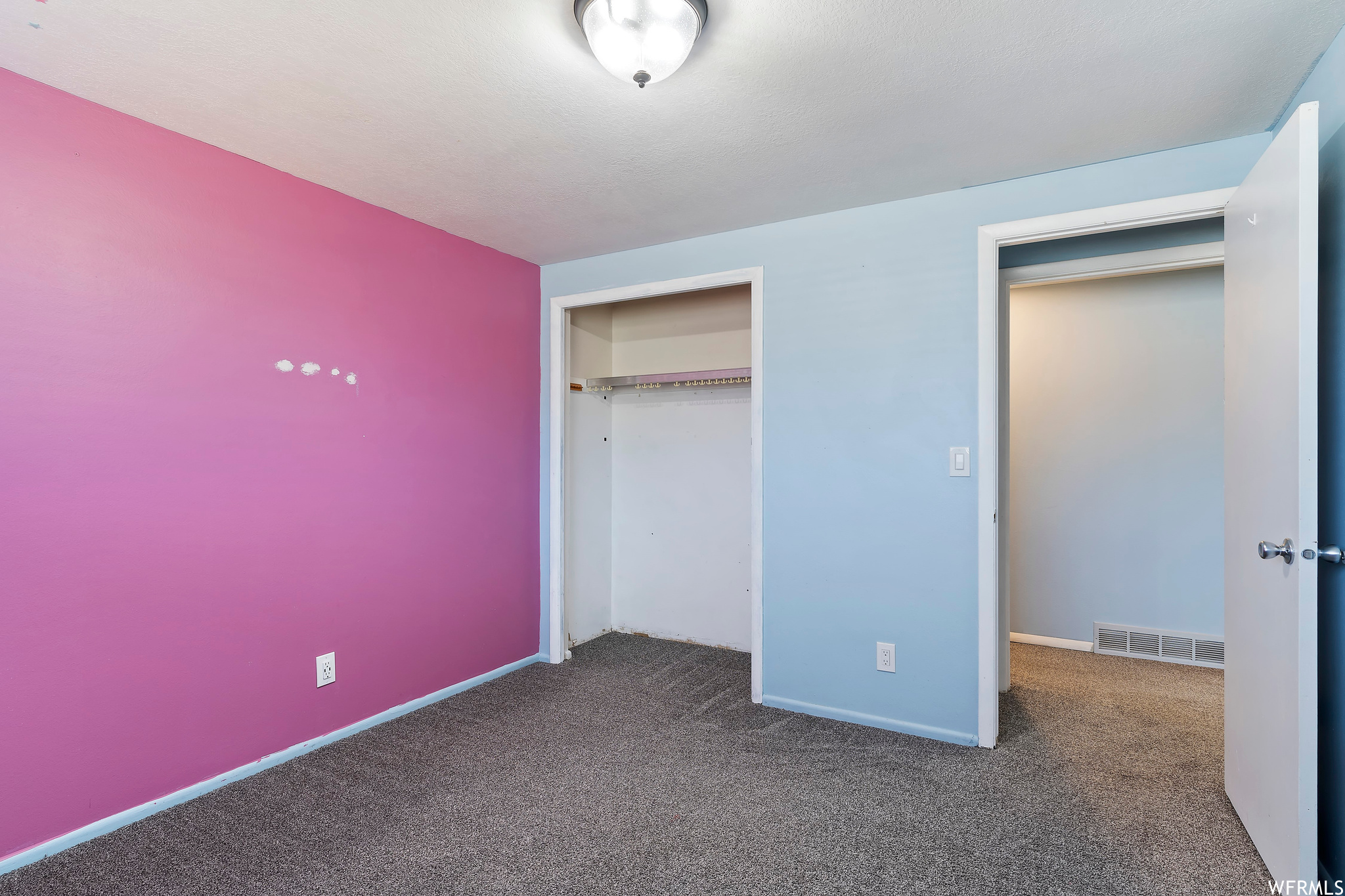 Unfurnished bedroom featuring dark carpet and a closet