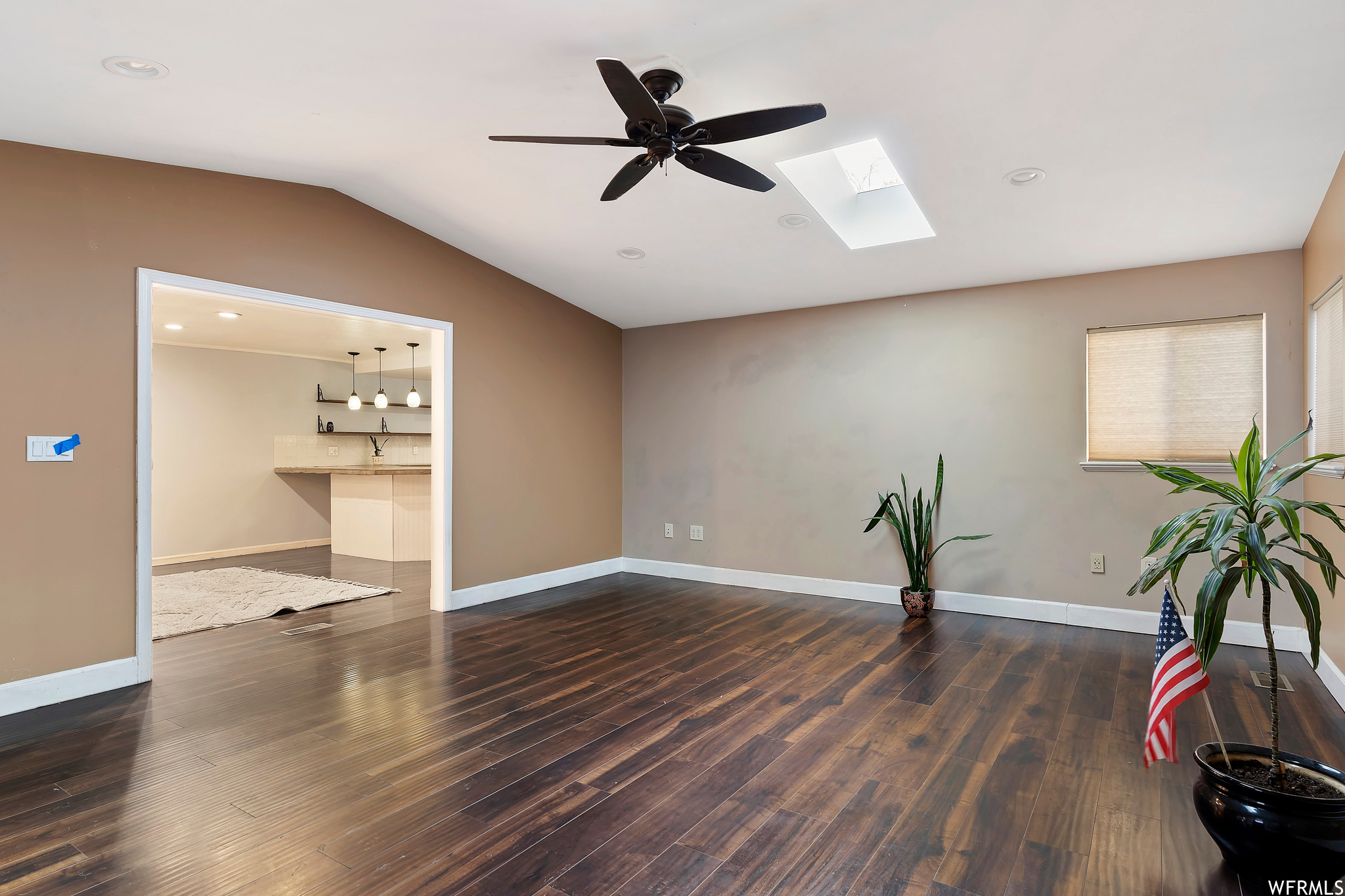 Spare room with dark hardwood / wood-style flooring, ceiling fan, and lofted ceiling with skylight