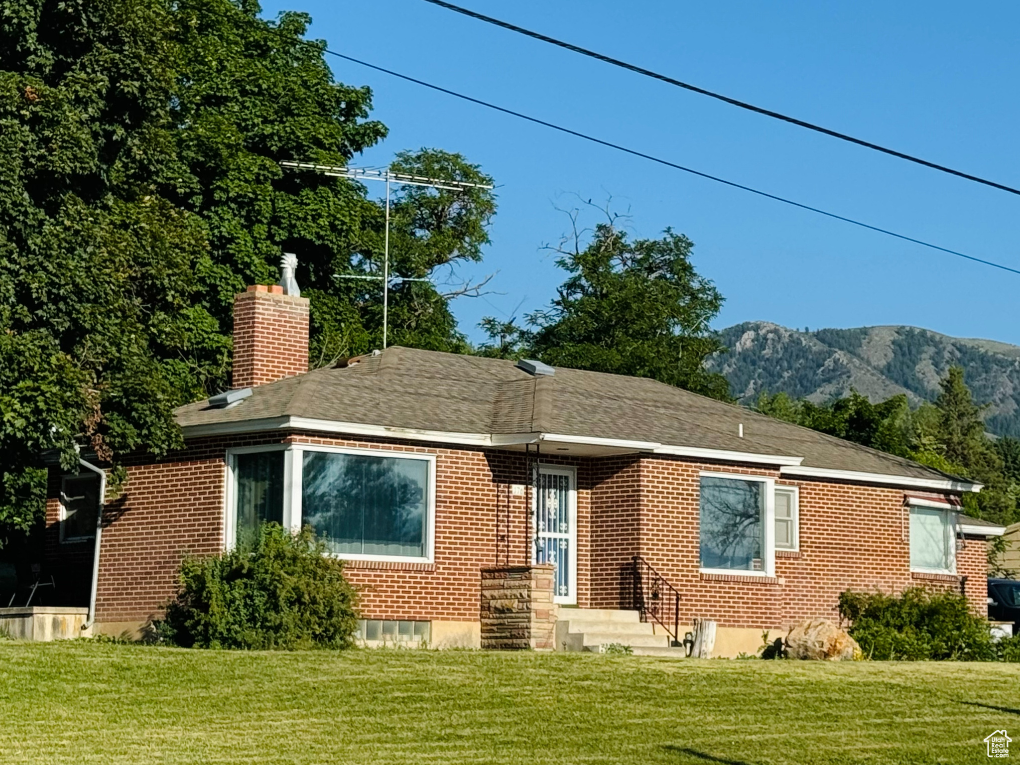 View of front of house with a mountain view and a front lawn