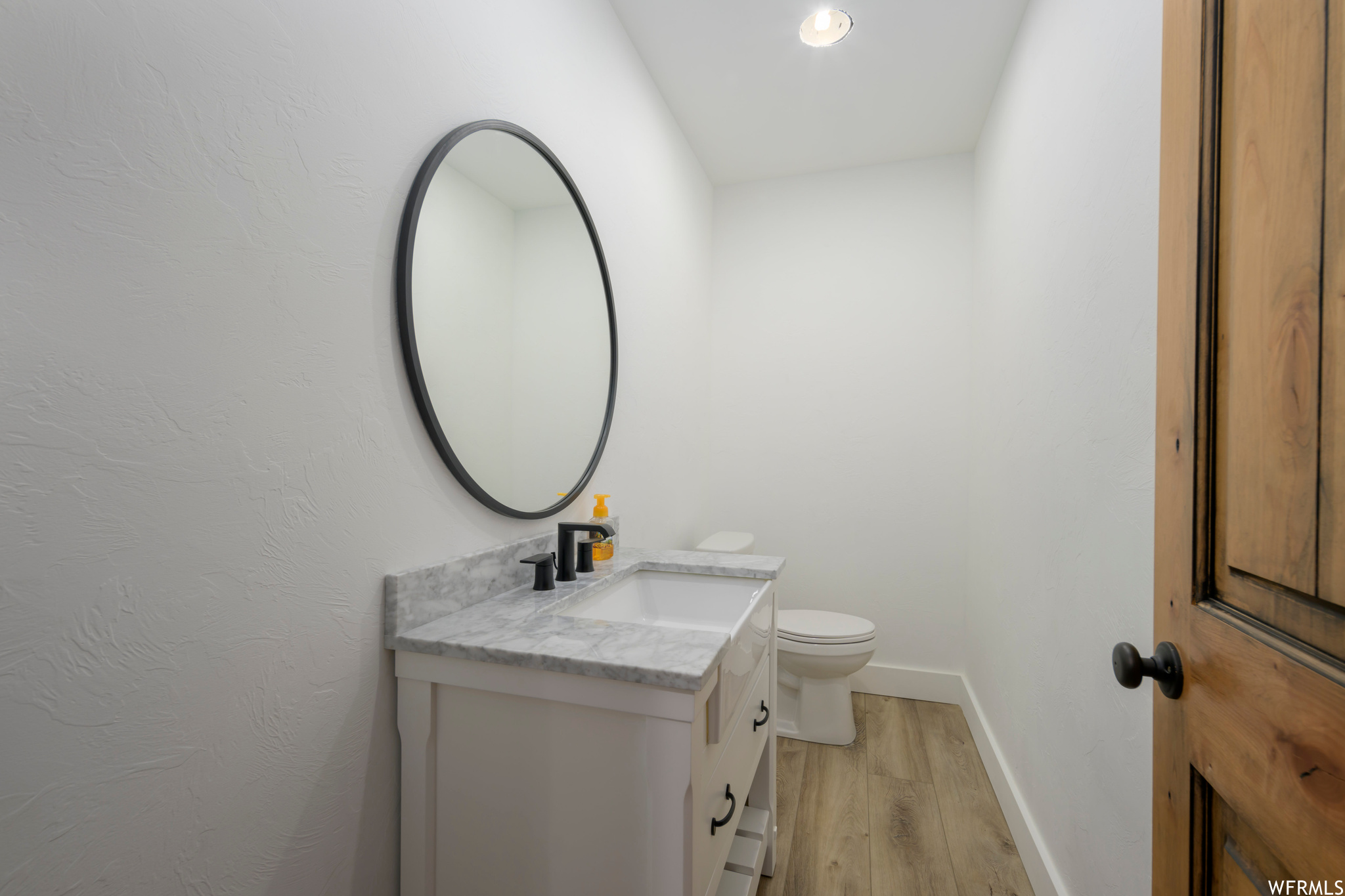 Bathroom with toilet, large vanity, and hardwood / wood-style flooring