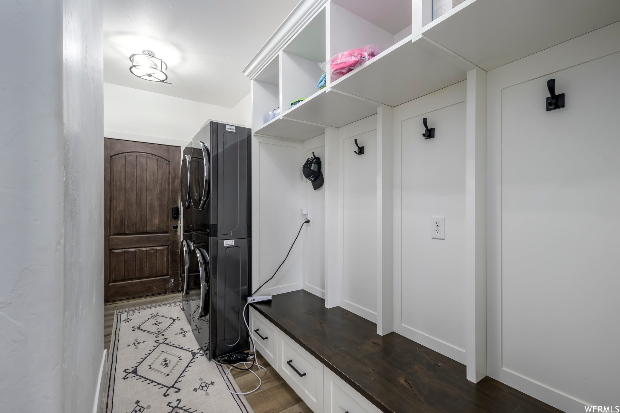 Mudroom featuring stacked washer / drying machine and hardwood / wood-style flooring