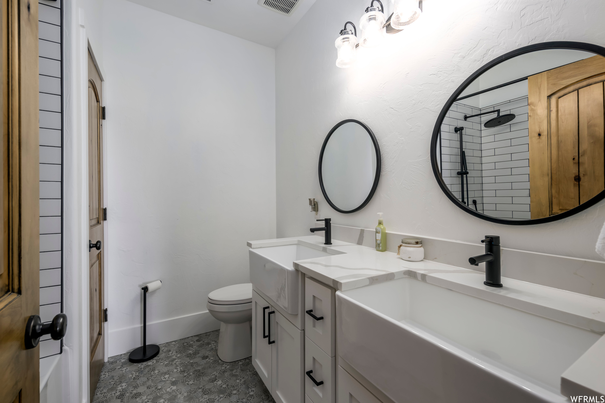 Bathroom featuring toilet, tile floors, and dual bowl vanity