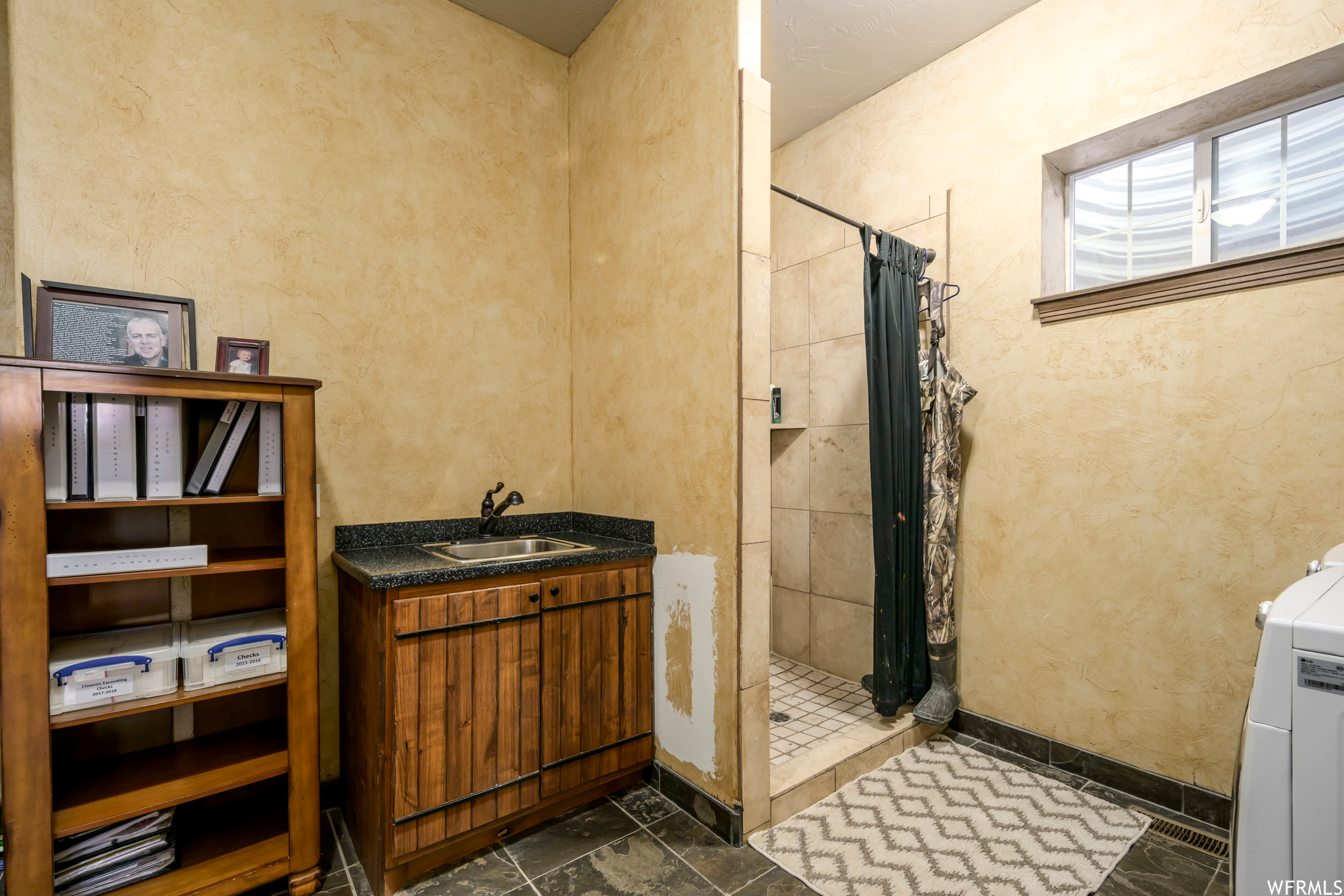 Bathroom with curtained shower, washer / dryer, vanity, and tile flooring