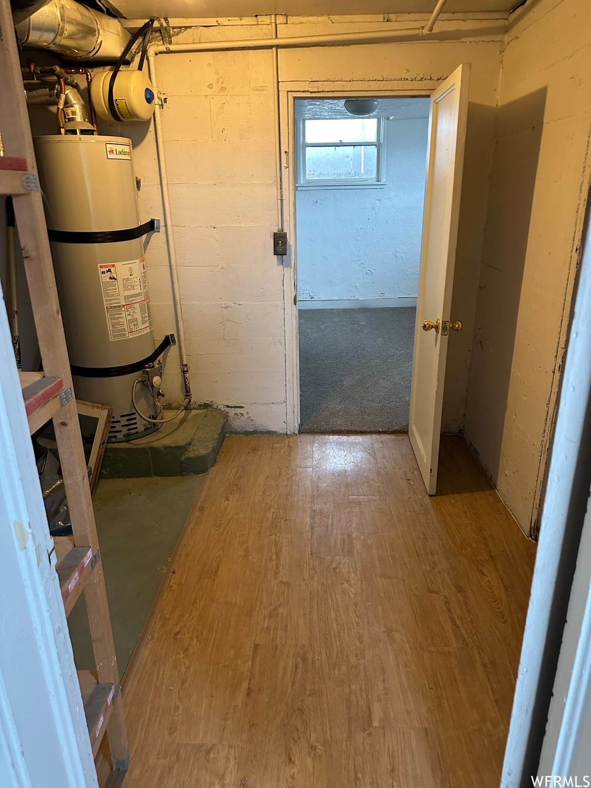 Hallway featuring secured water heater and hardwood / wood-style flooring