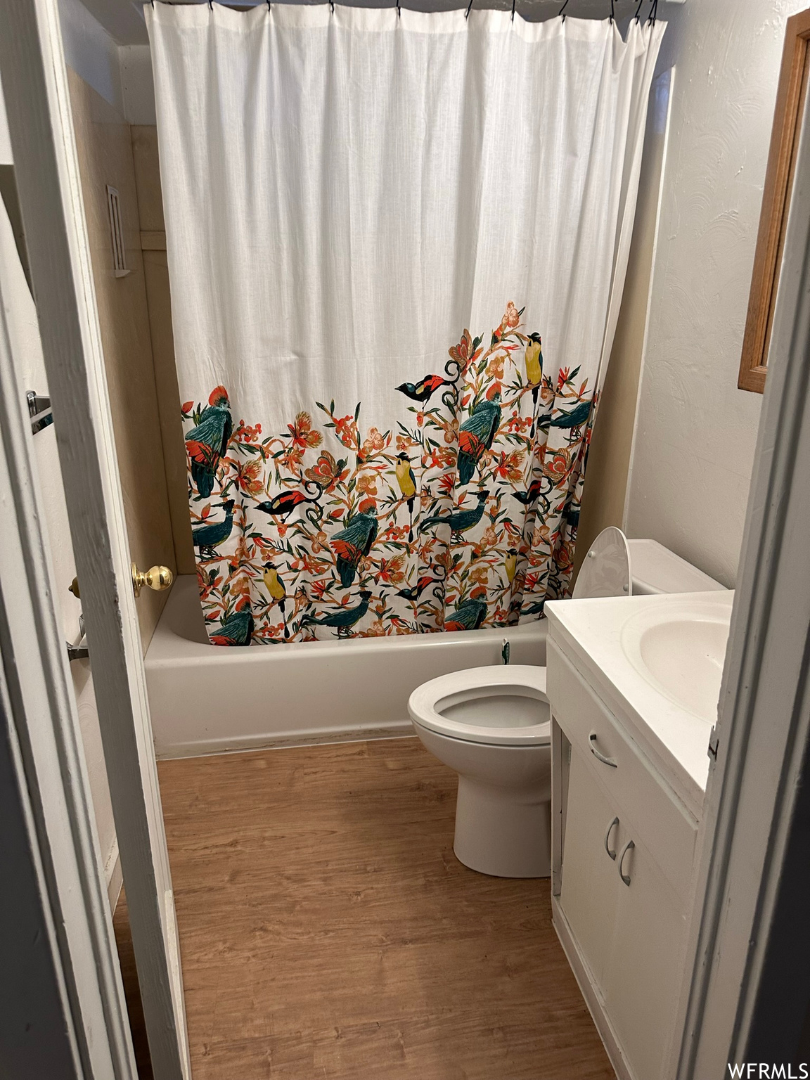 Full bathroom with toilet, shower / tub combo, hardwood / wood-style flooring, and vanity