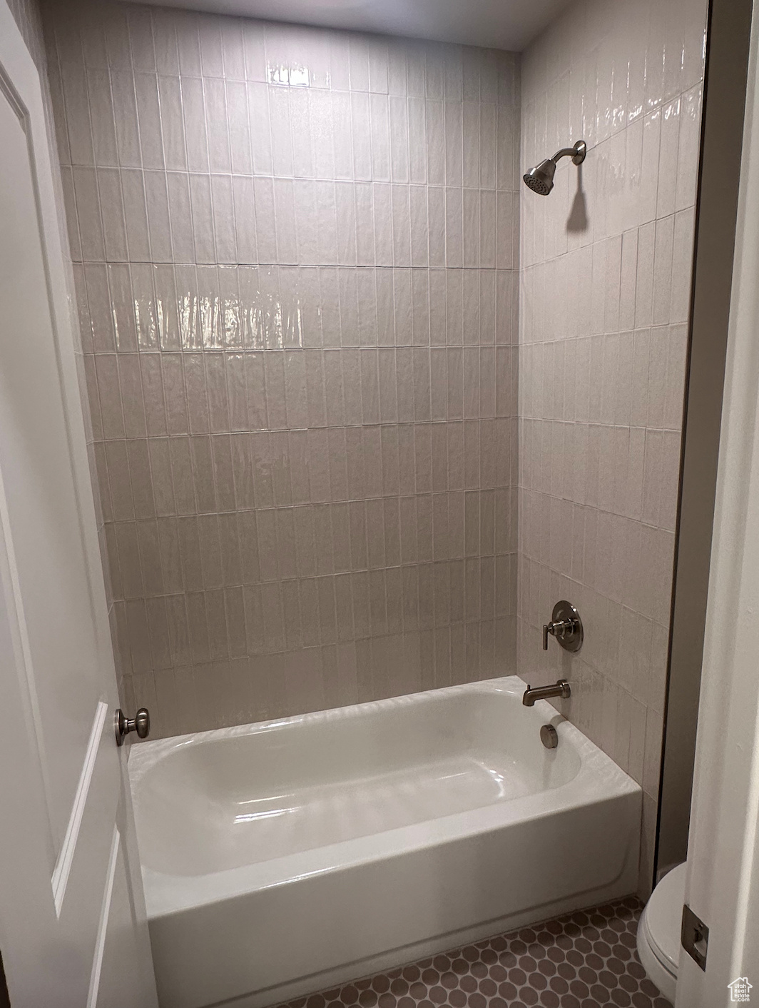 Bathroom featuring tiled shower / bath combo, toilet, and tile patterned floors