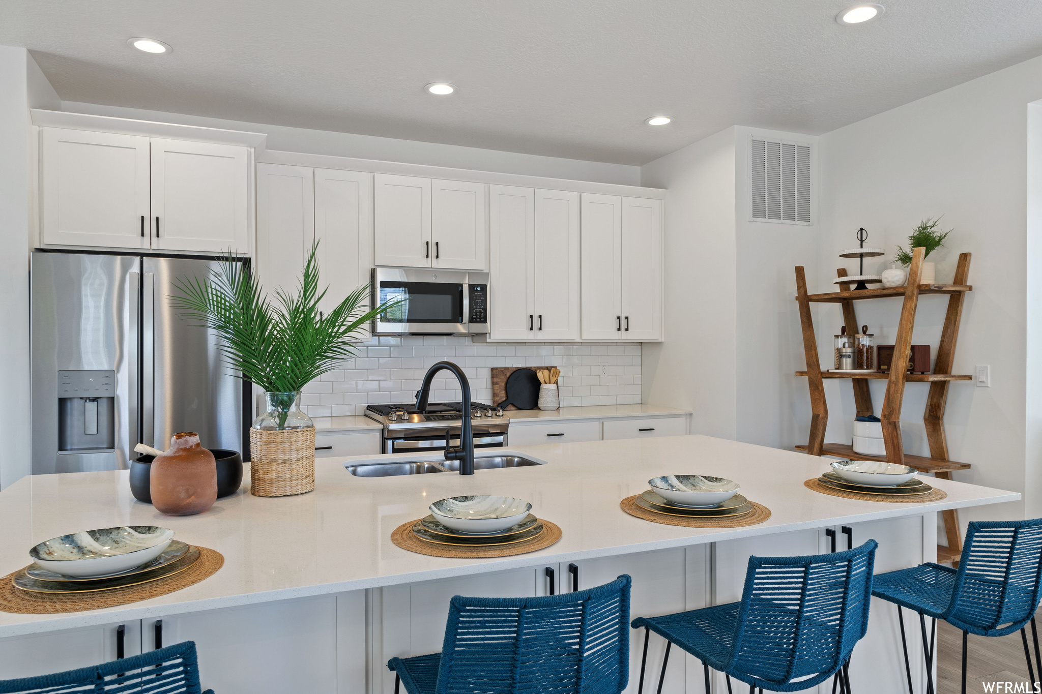 Kitchen with a breakfast bar, white cabinets, appliances with stainless steel finishes, and backsplash