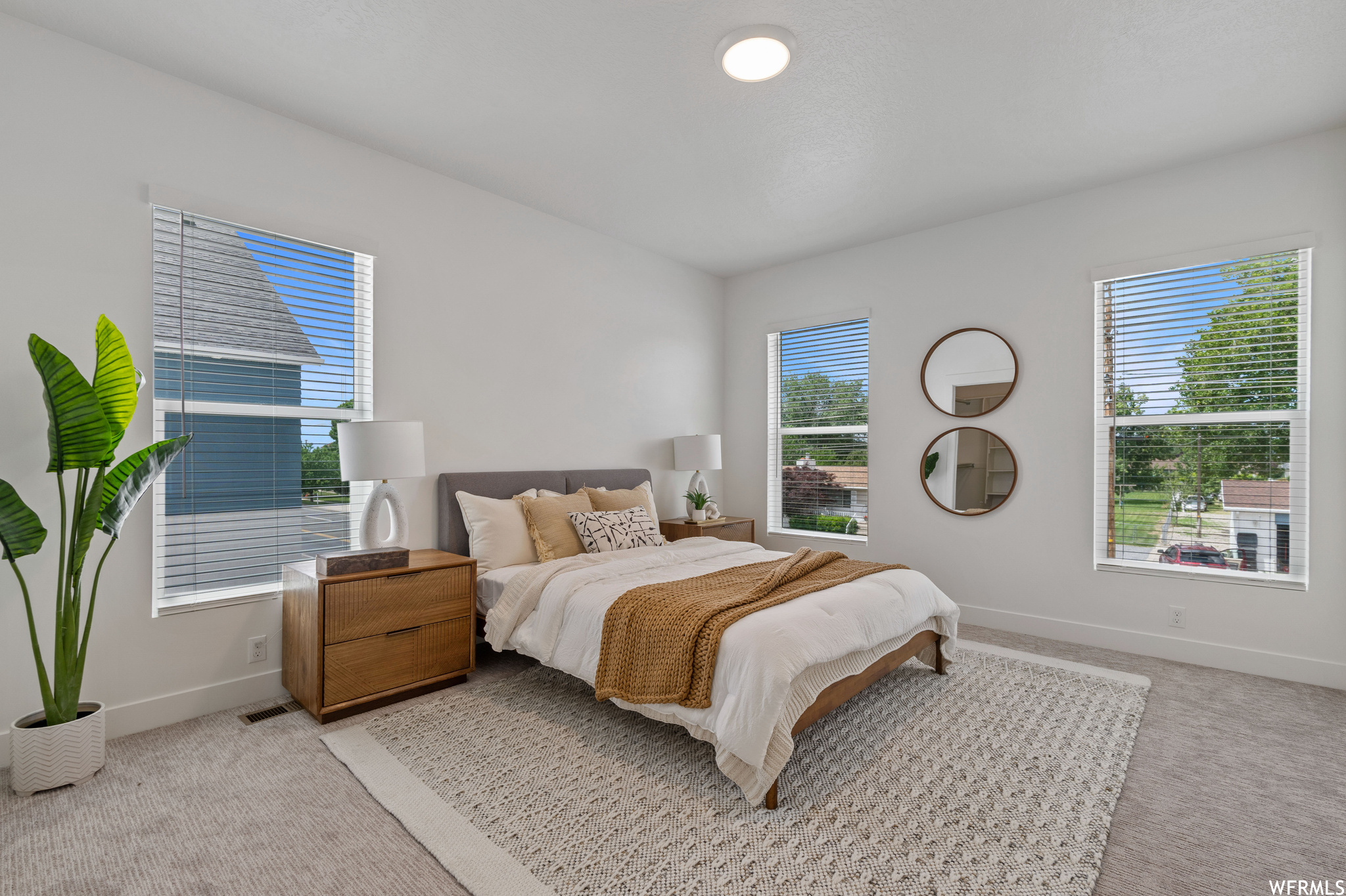 Bedroom with multiple windows and light carpet