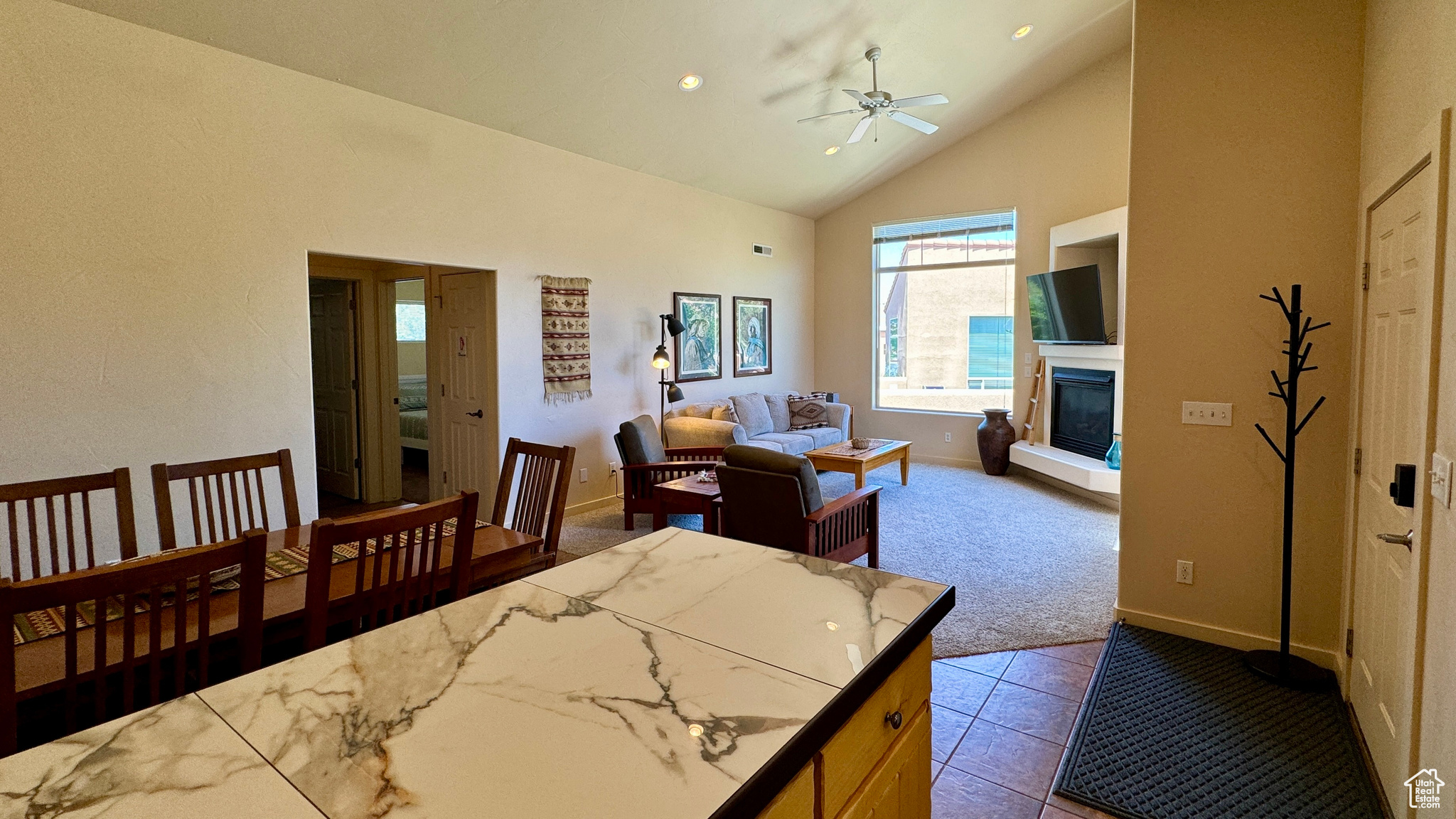 Interior space featuring light carpet, high vaulted ceiling, and ceiling fan