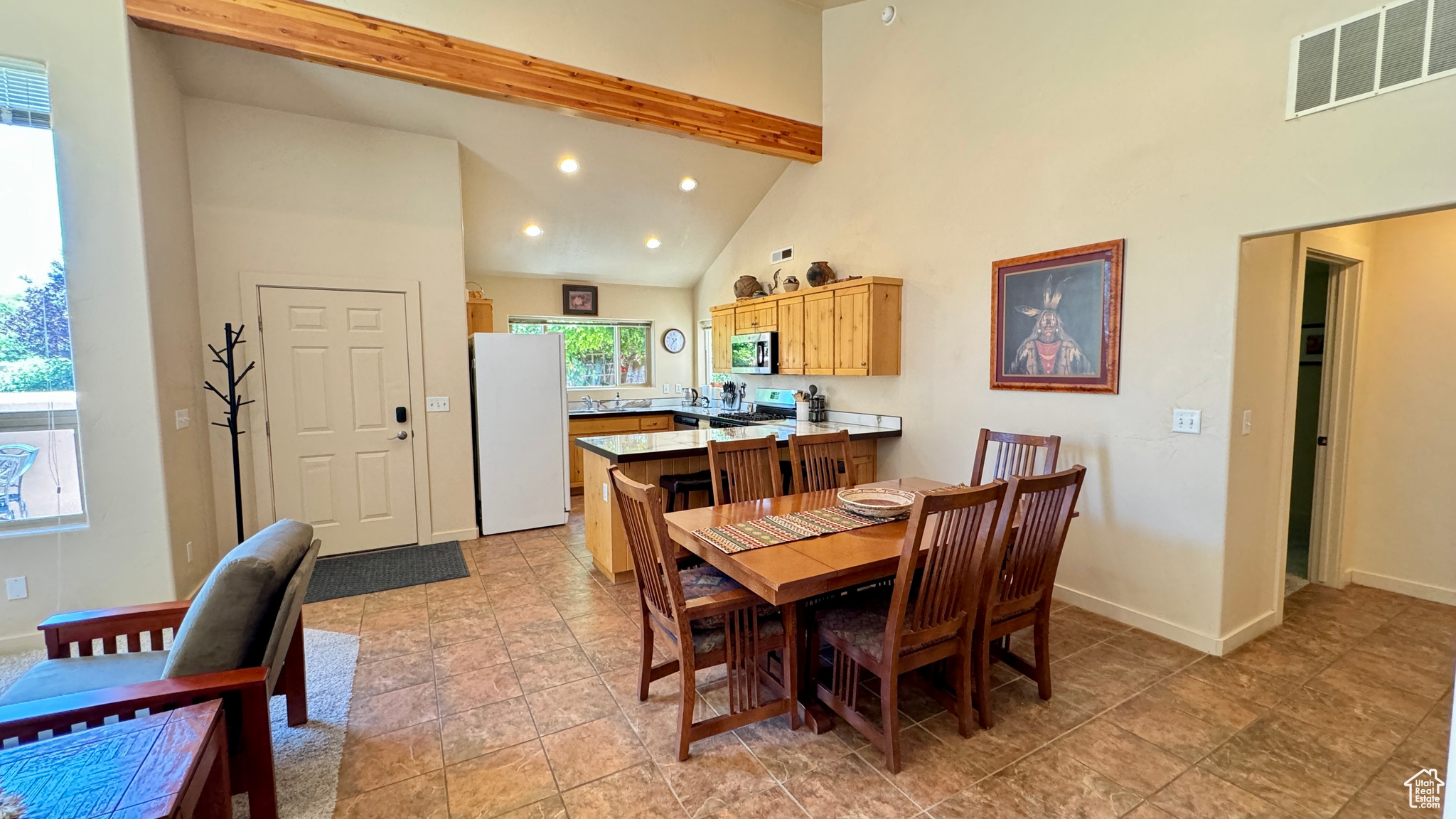 Tiled dining space featuring high vaulted ceiling and beamed ceiling