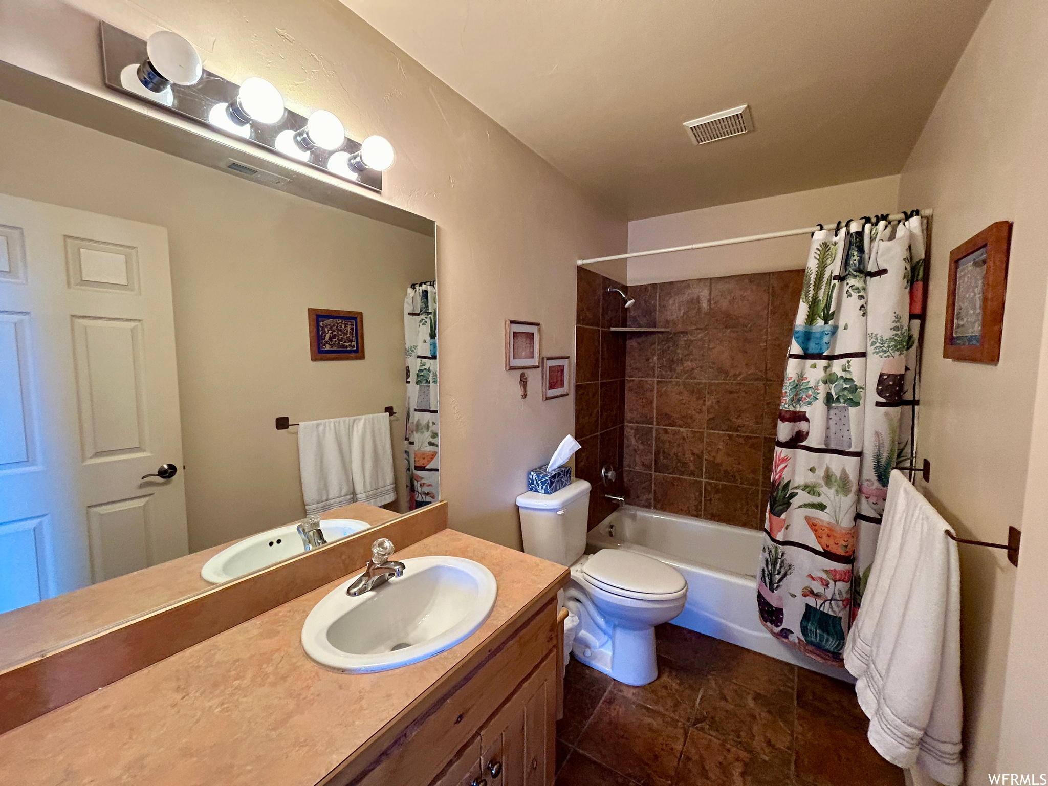 Guest bathroom with shower / tub combo with curtain, oversized vanity, toilet, and tile flooring