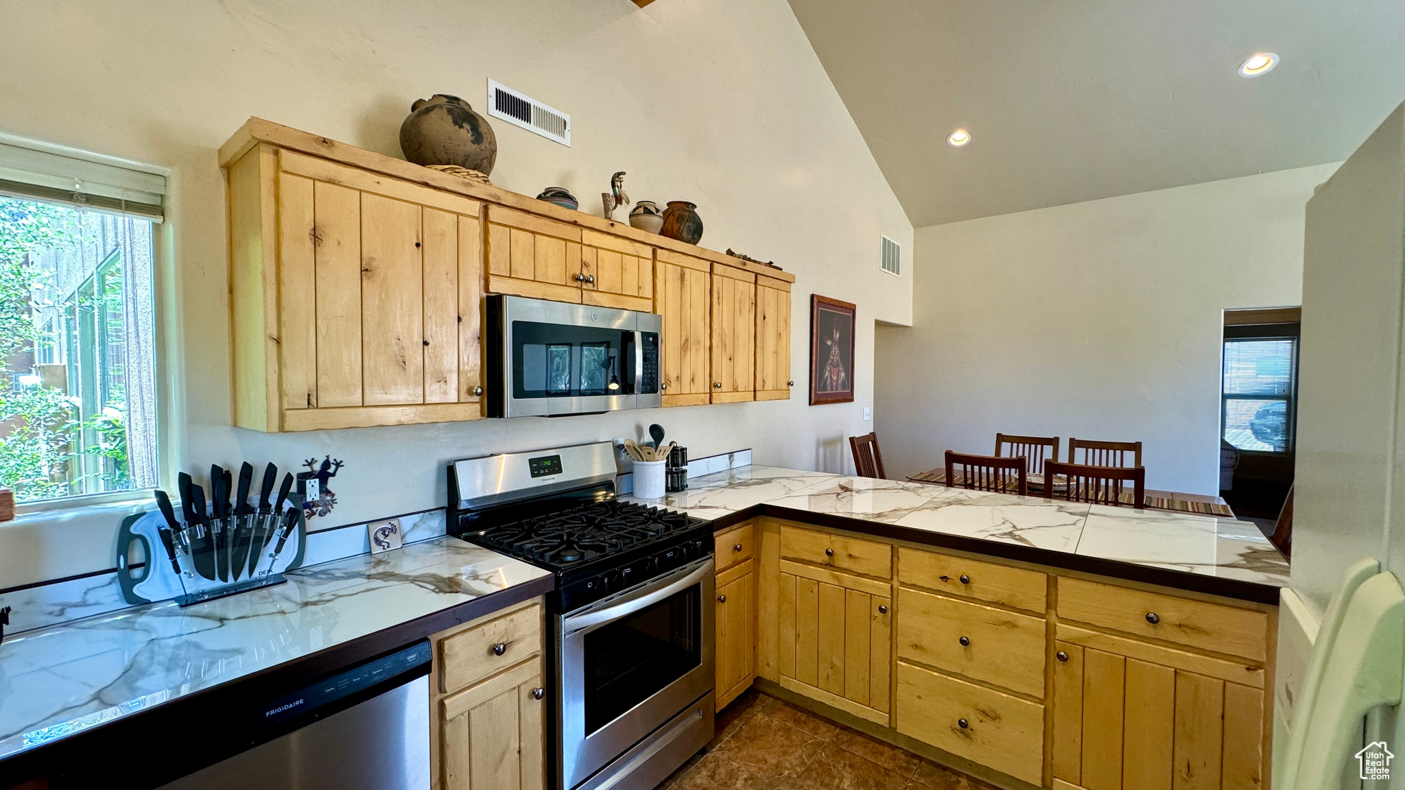 Kitchen featuring dark tile patterned flooring, light brown cabinets, and stainless steel appliances