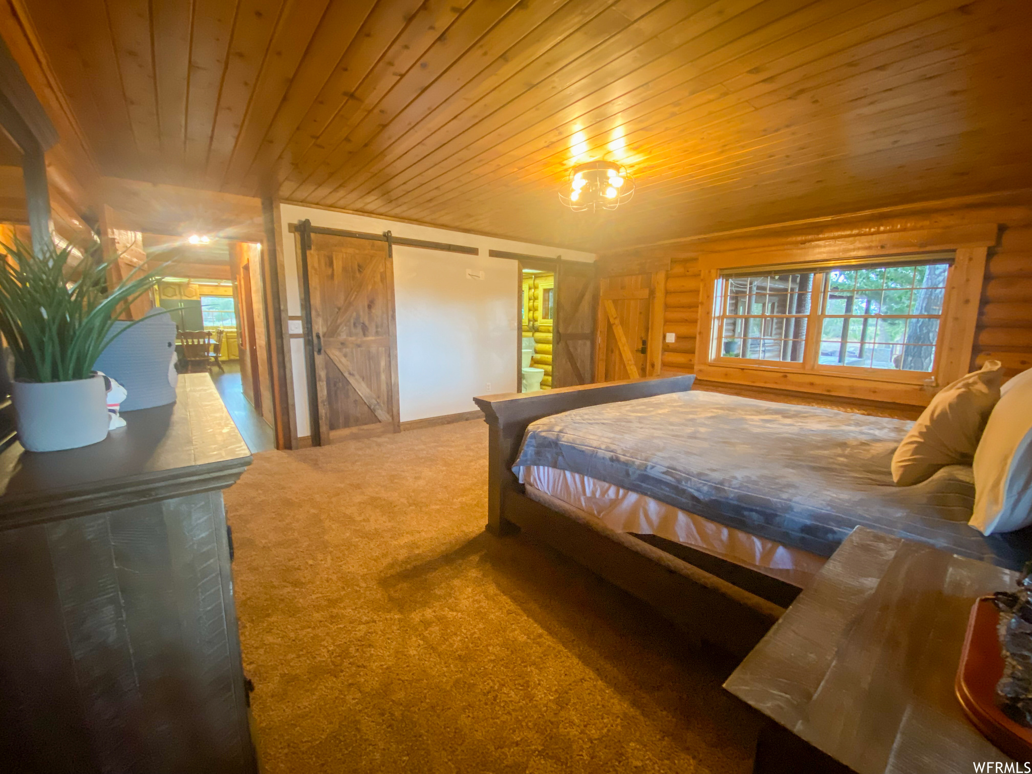 Carpeted bedroom featuring a barn door and wood ceiling