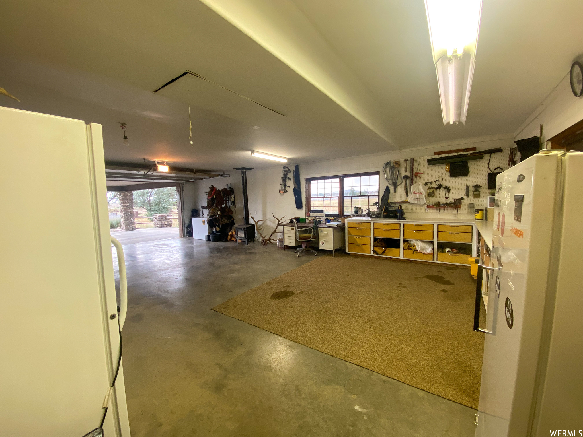 Garage featuring white fridge and a workshop area