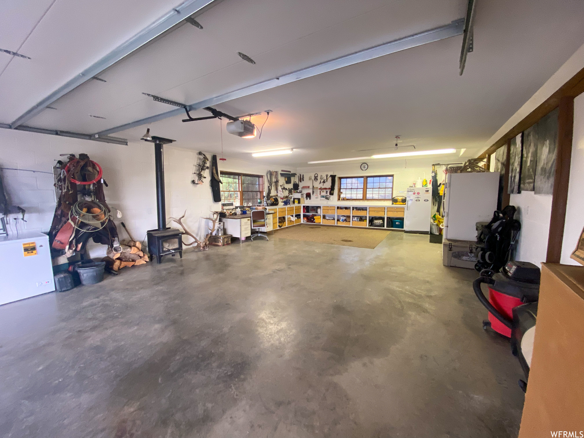 Garage with white refrigerator, a garage door opener, and a workshop area