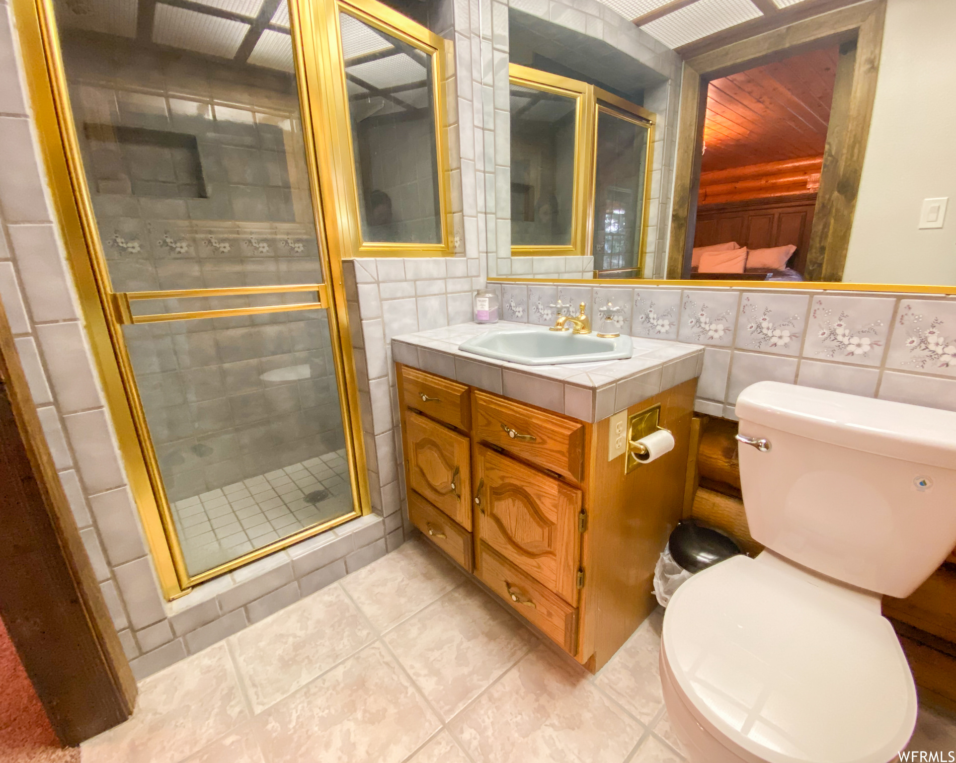Bathroom featuring oversized vanity, tile walls, tile floors, tasteful backsplash, and a shower with door