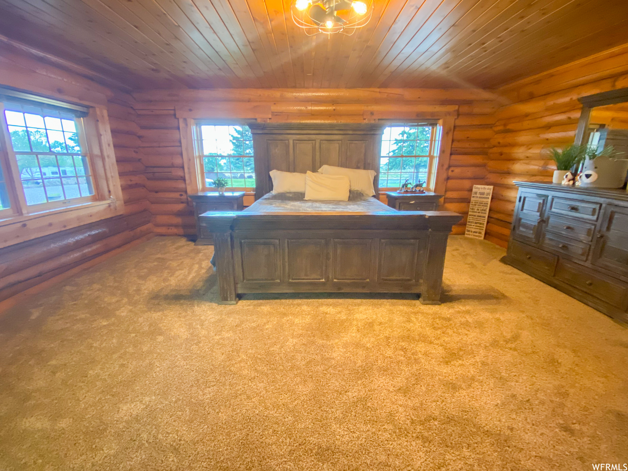 Home office with log walls, light colored carpet, and wooden ceiling