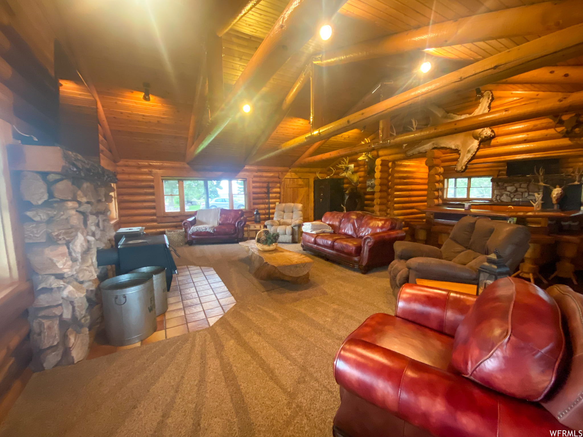 Carpeted living room featuring wood ceiling, high vaulted ceiling, and rustic walls