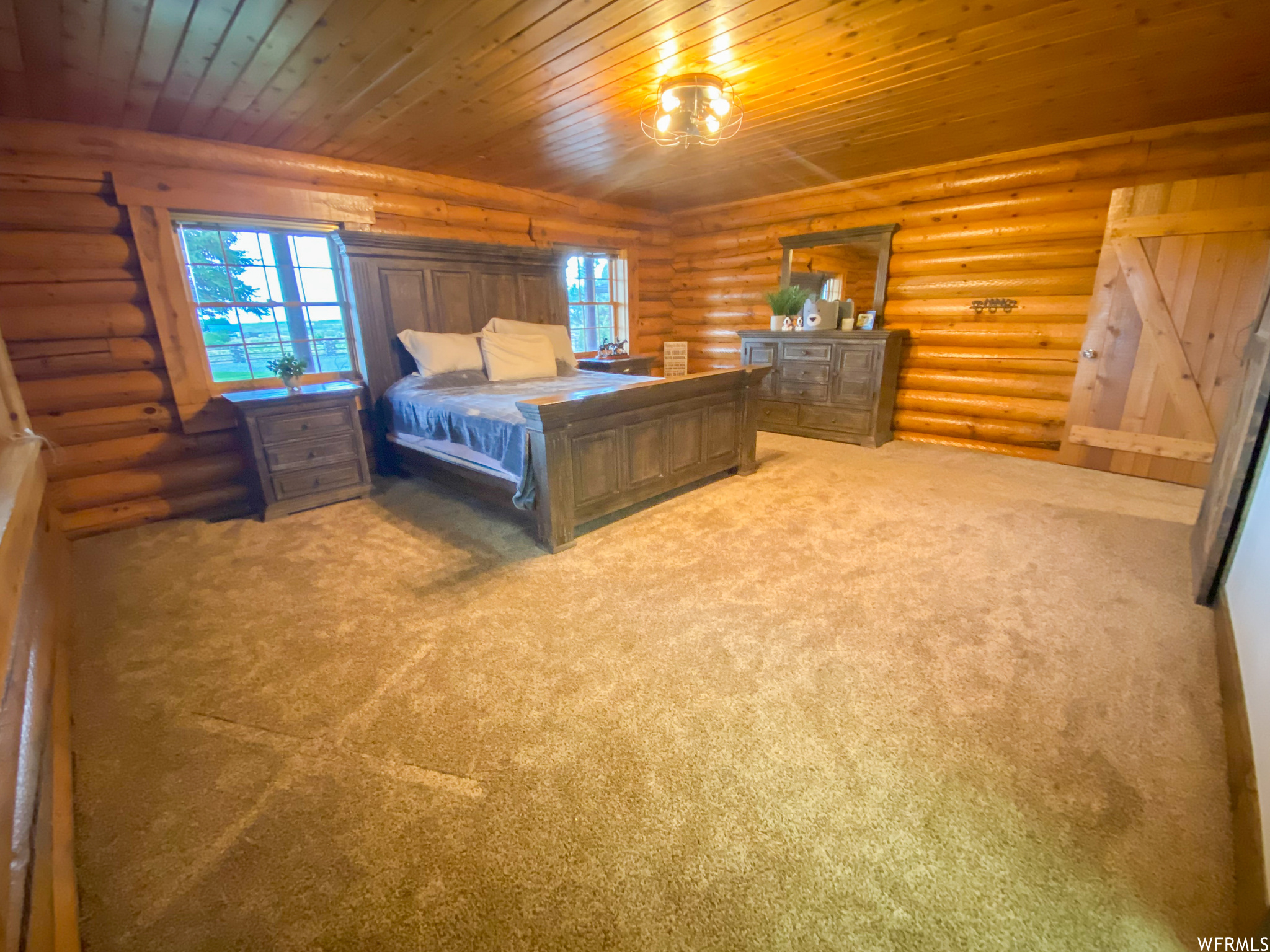 Bedroom featuring carpet, multiple windows, wood ceiling, and rustic walls