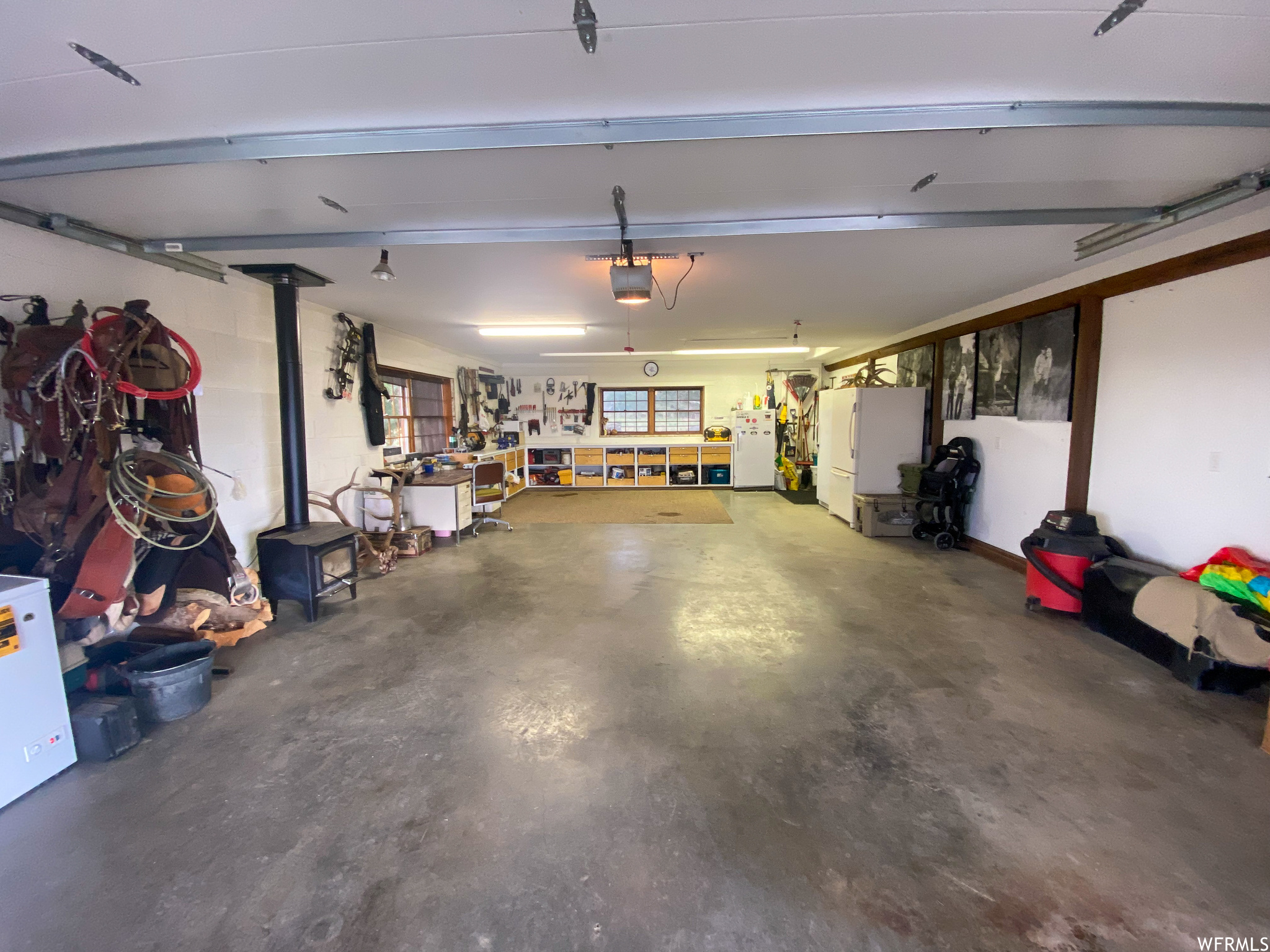 Garage with a garage door opener, a workshop area, and white fridge